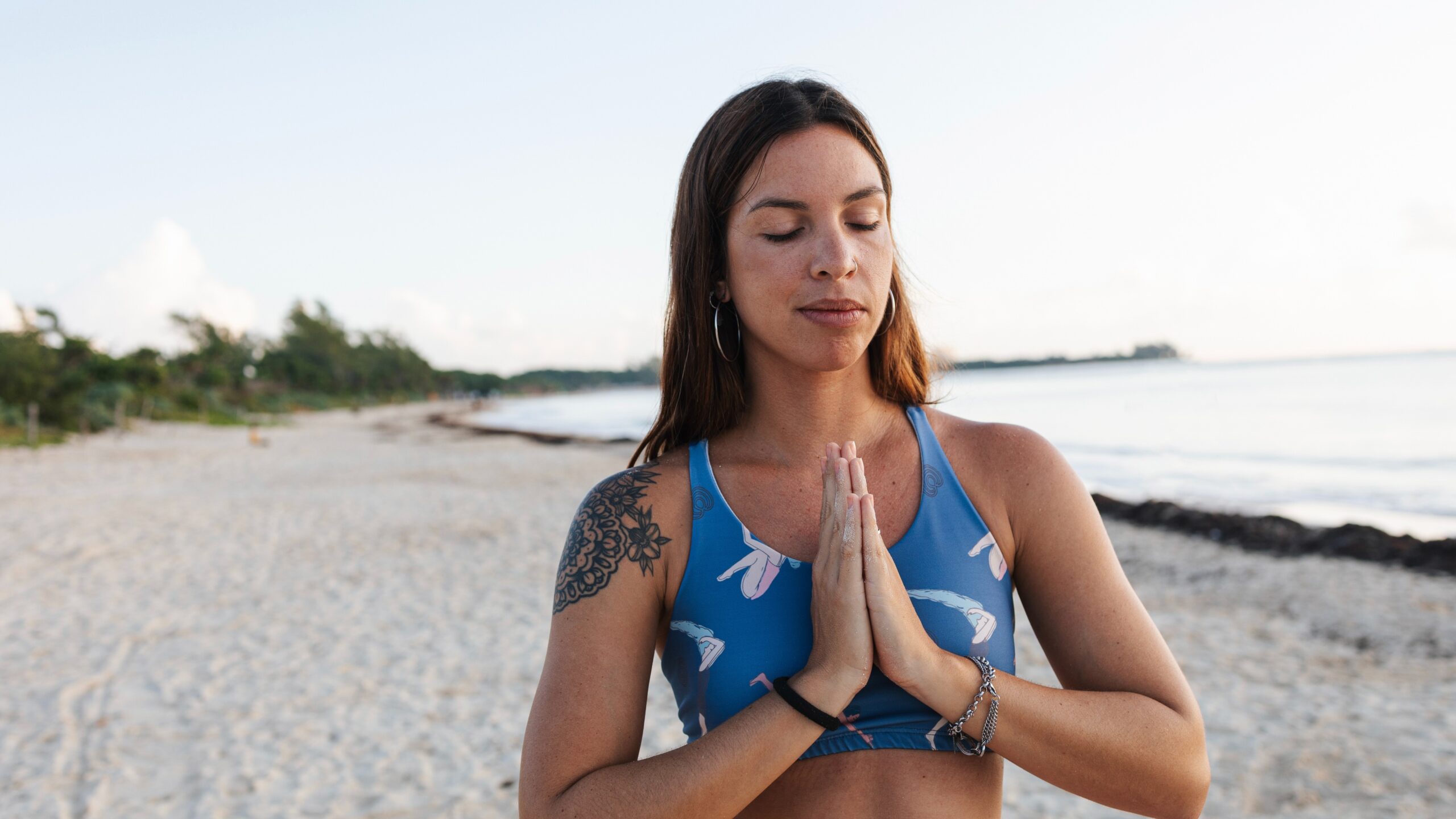 woman meditating on the beach in the summer