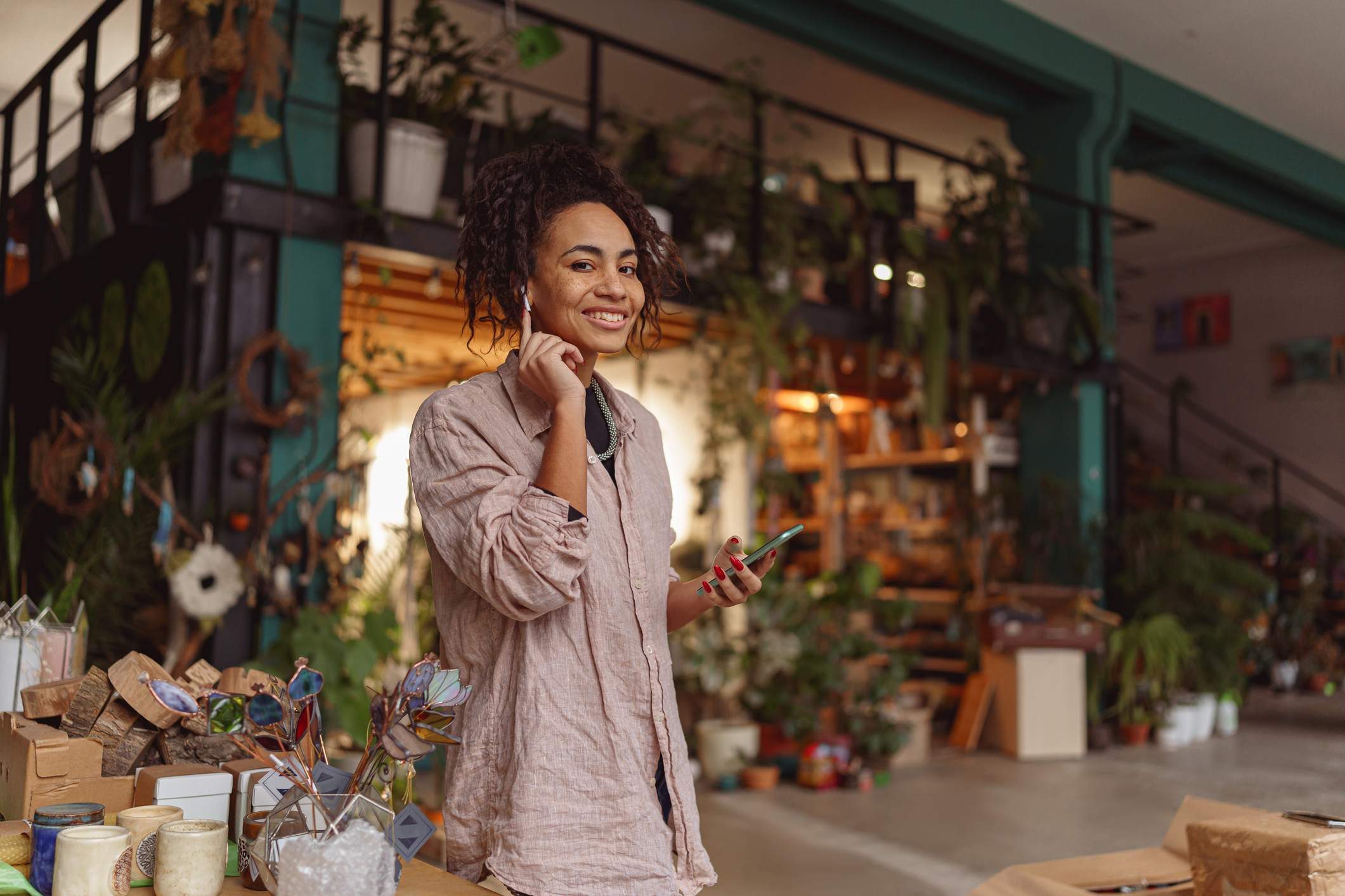 Smiling woman florist decorator listening music during break in floral studio