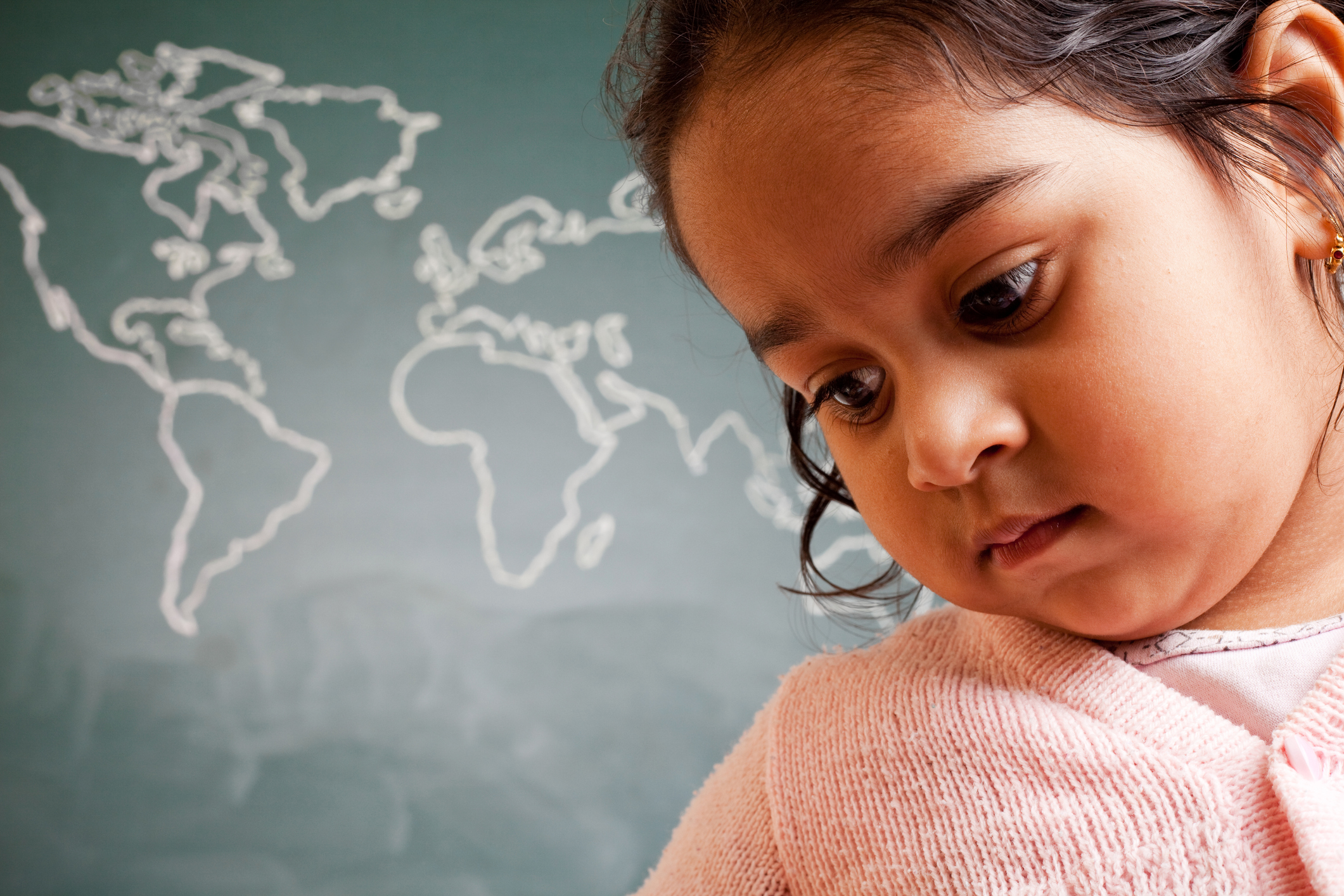 Pensive Little Indian Preschool Girl in Front of World Map