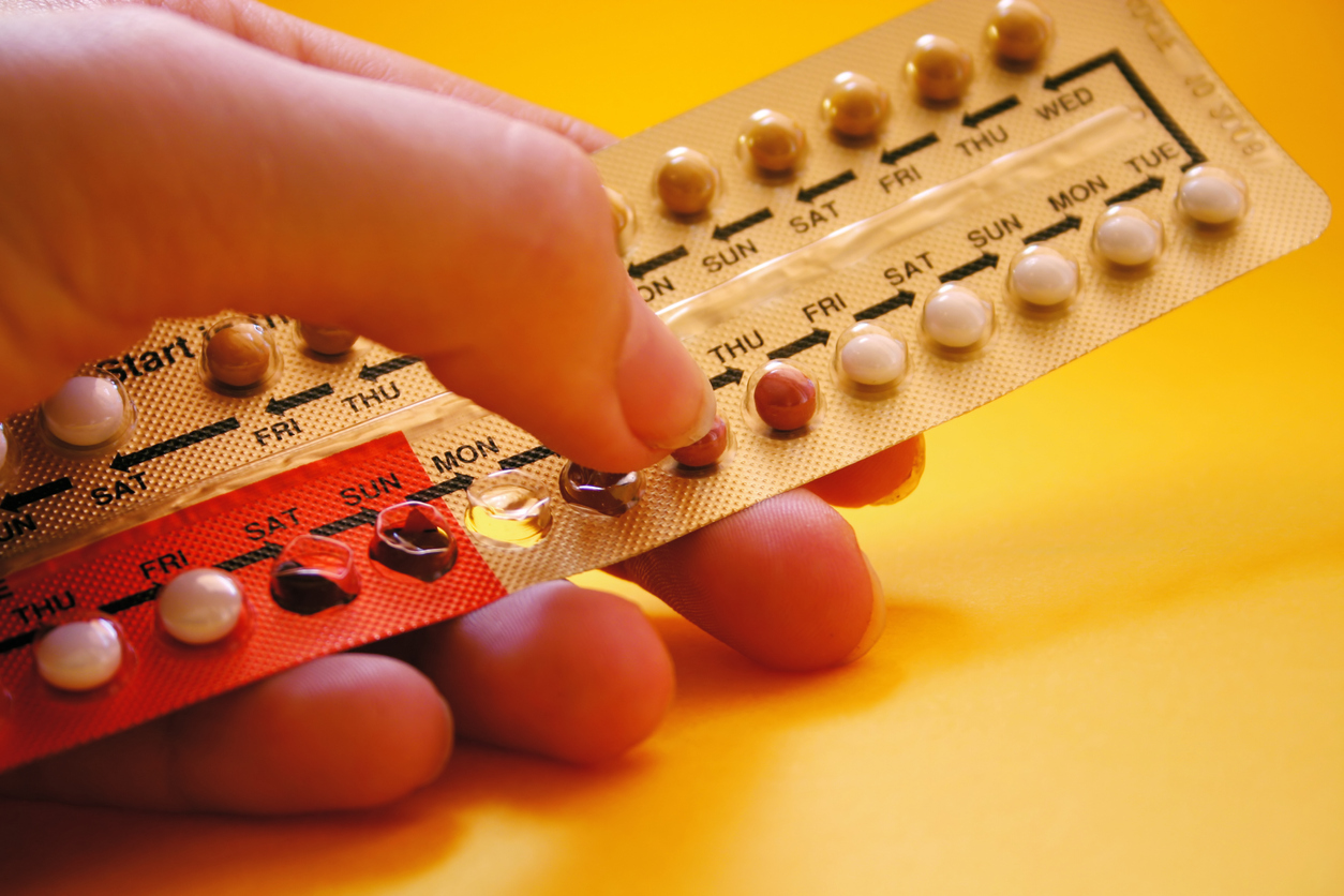 Close up of hand holding a pack of oral contraceptives