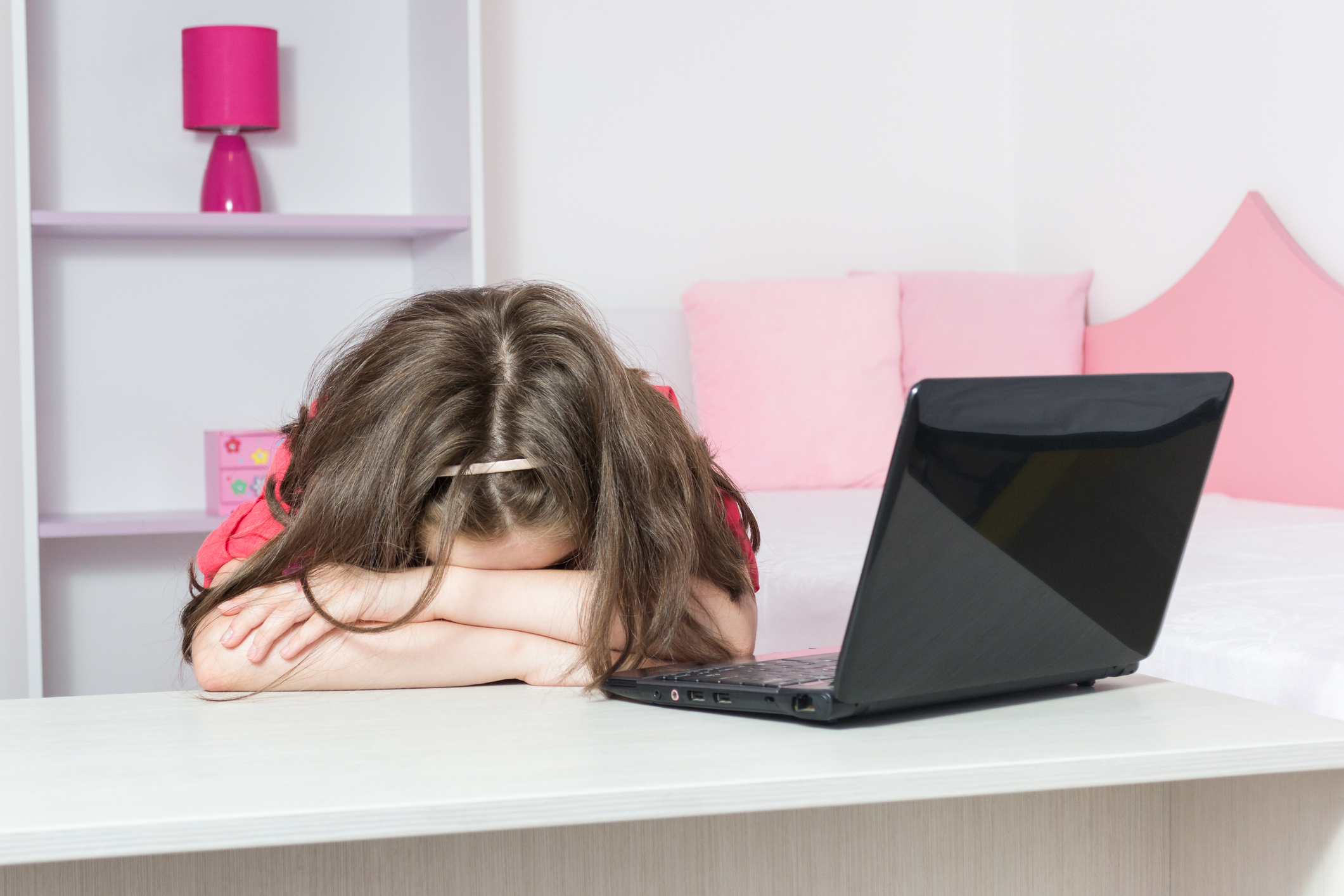 Beautiful young girl exhausted in front of laptop