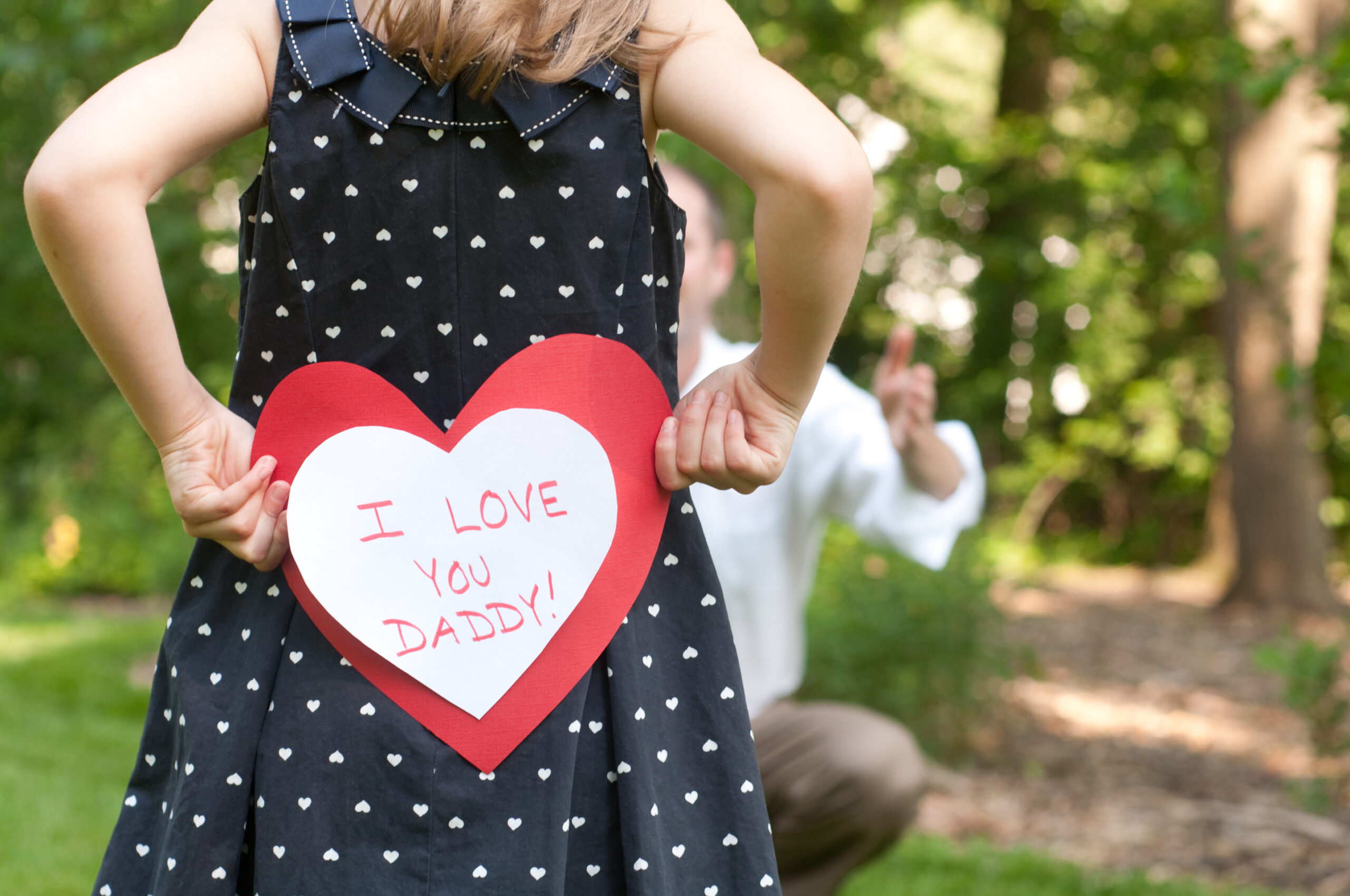 Girl holds "I Love You Daddy!" card for father