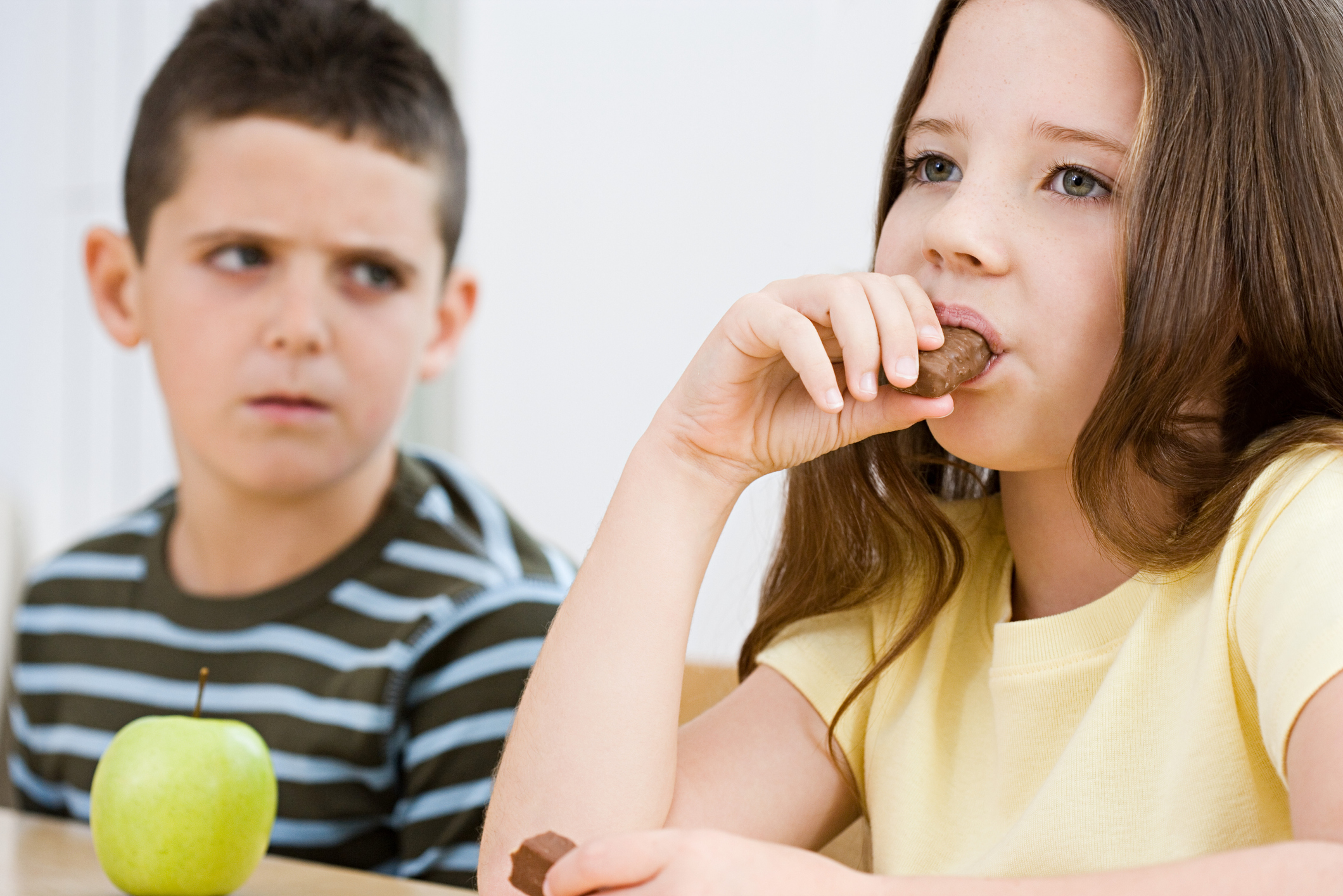 Boy looking at girl eating chocolate bar