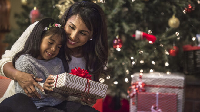 Mamá latina entregando regalo a su hija en Navidad