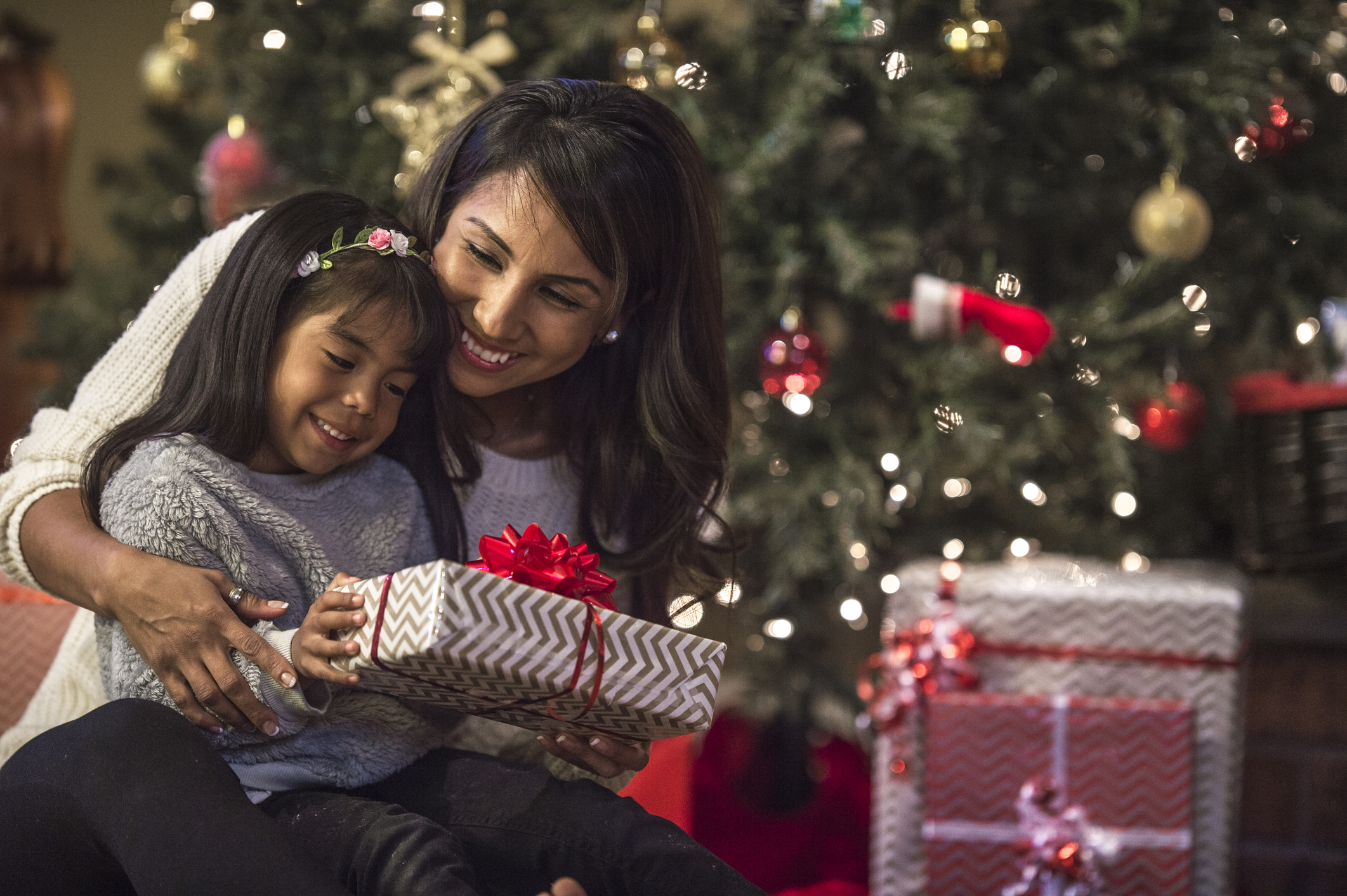 Mamá latina entregando regalo a su hija en Navidad