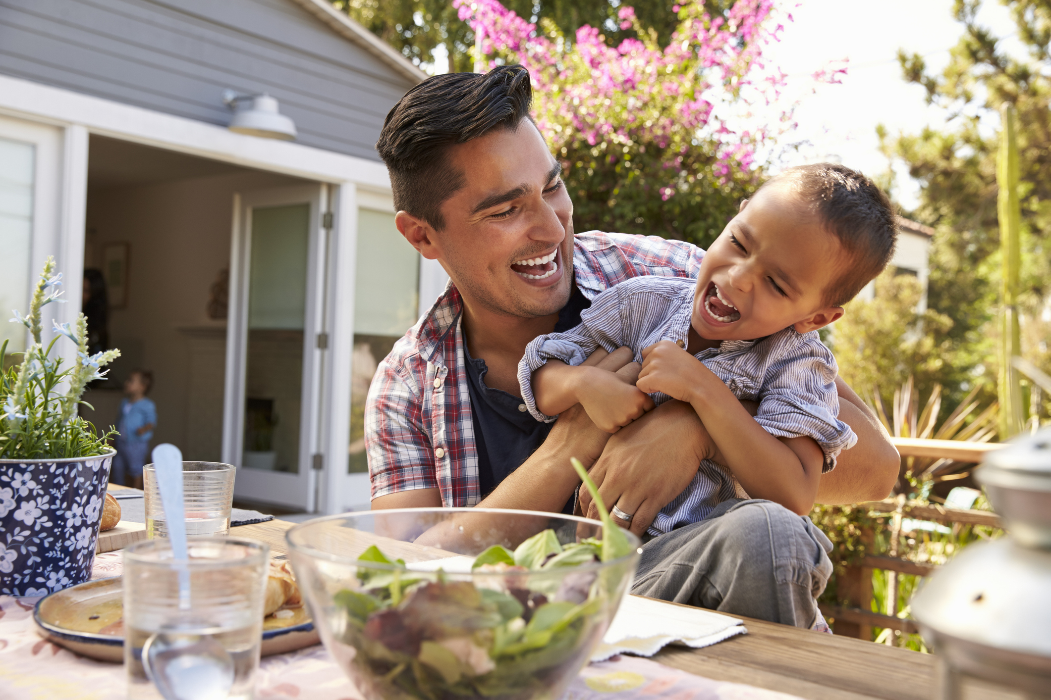 Father And Son Eating Outdoor Meal In Garden Together