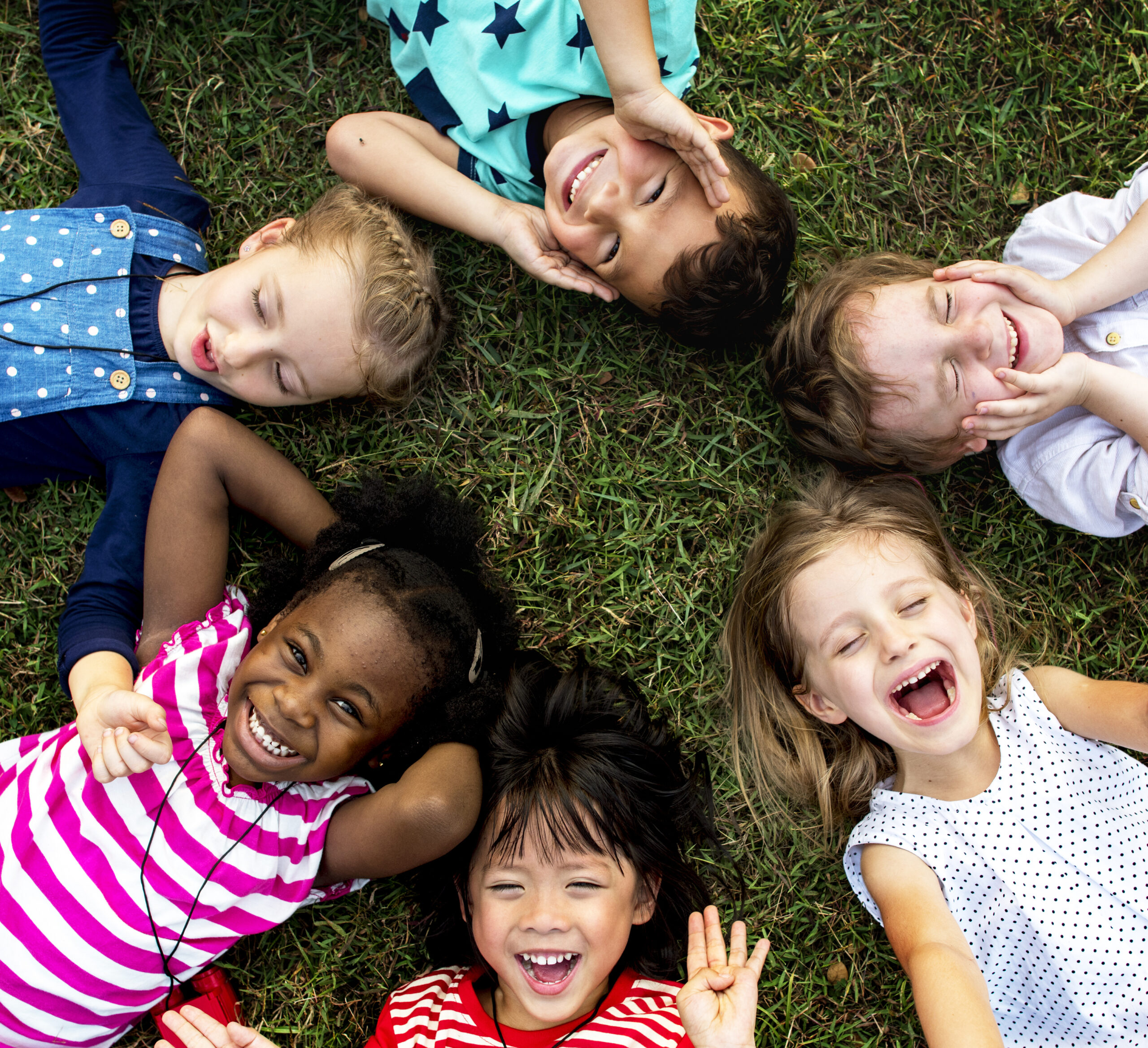 Group of kindergarten kids lying on the grass at park and relax with smiling