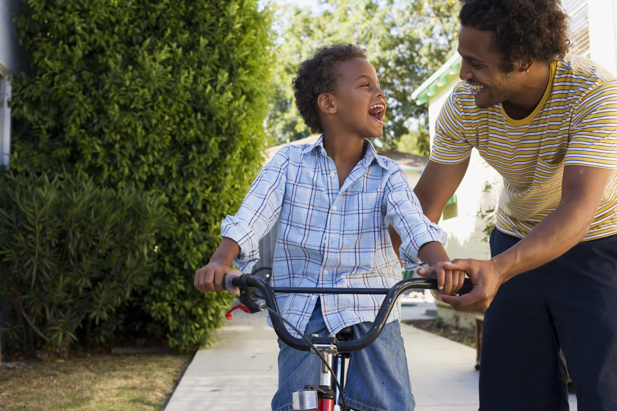 Father teaching son to ride bicycle in driveway