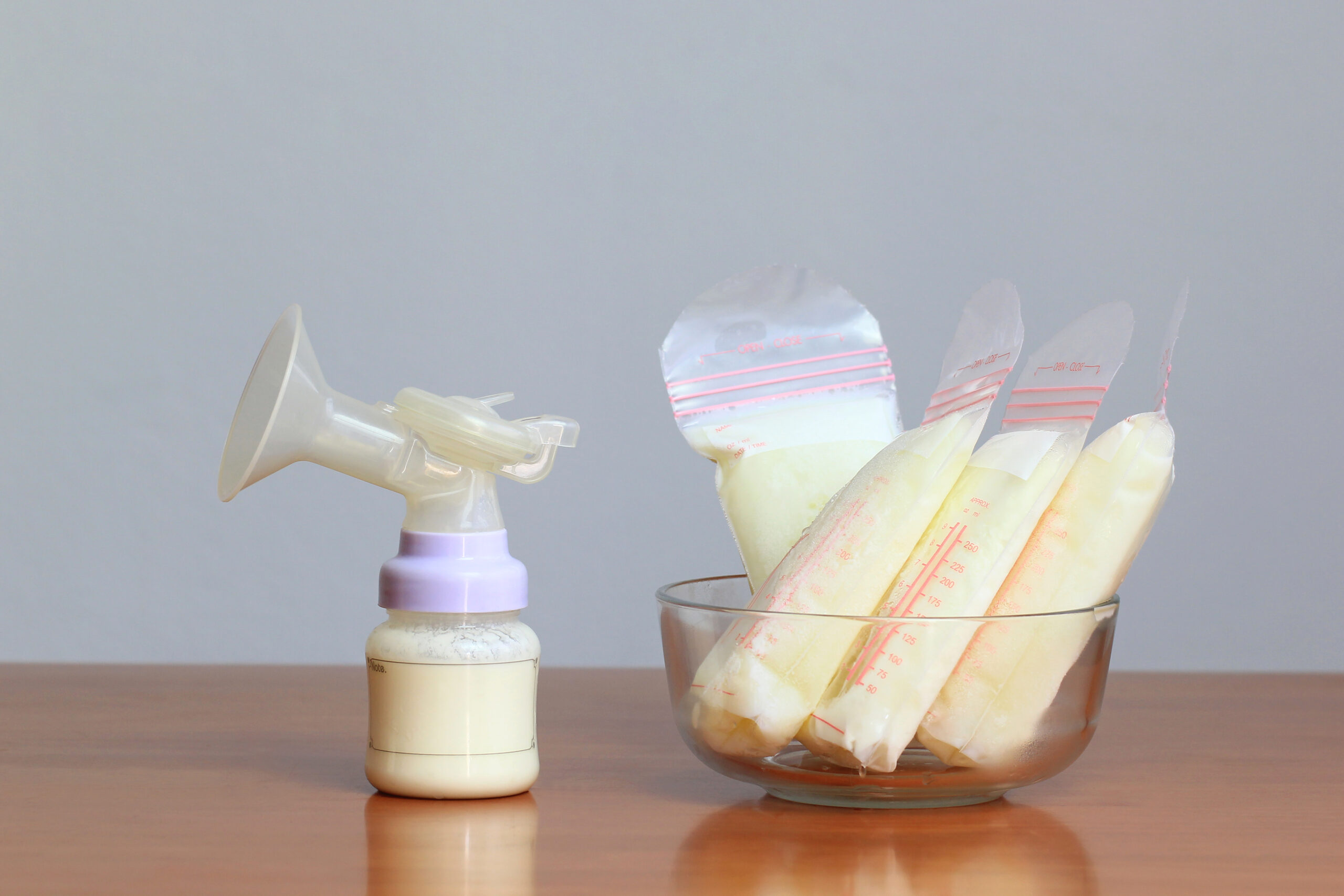 Bottles and frozen breast milk storage bags for new baby on wooden table