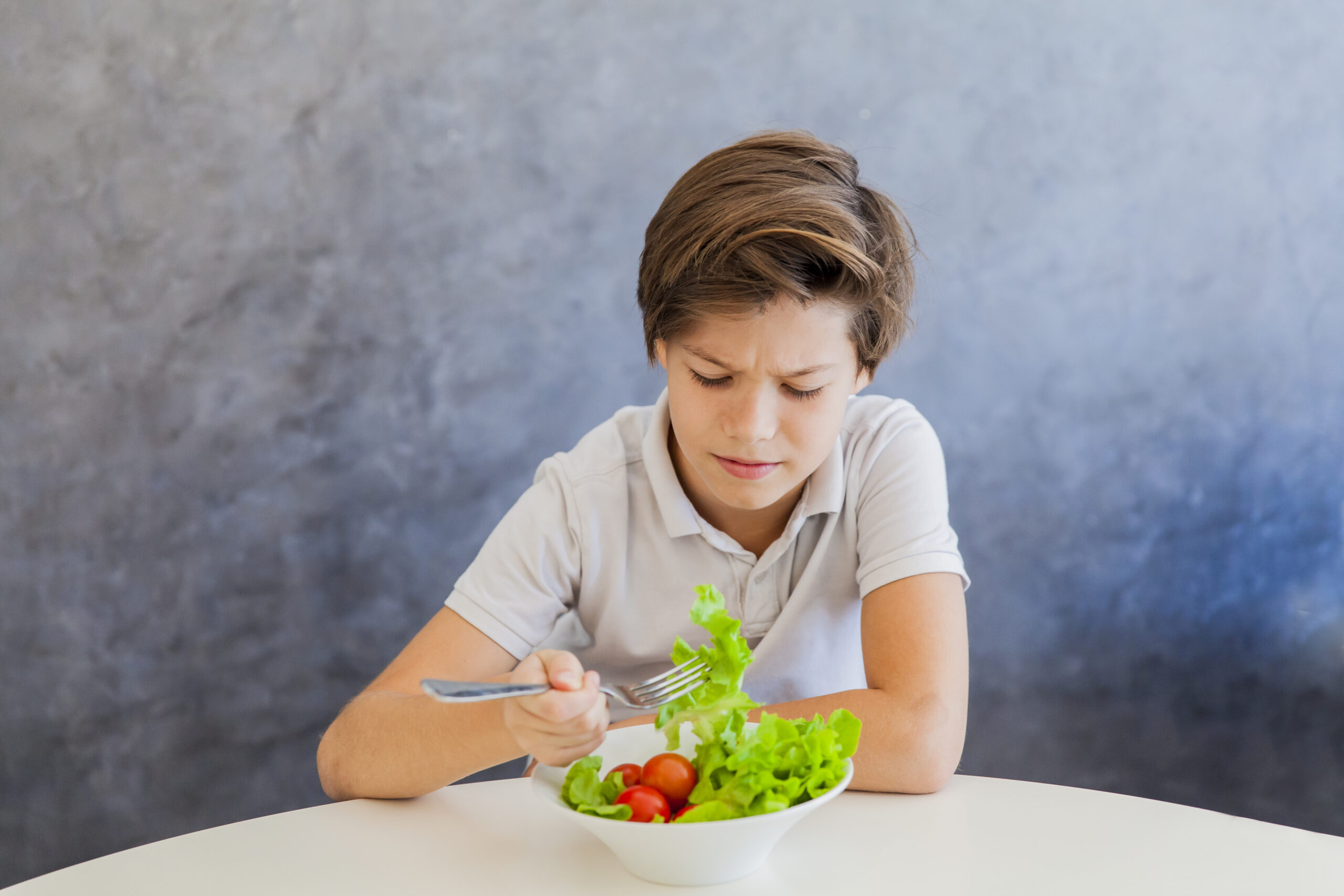 Cute teen boy eating salad