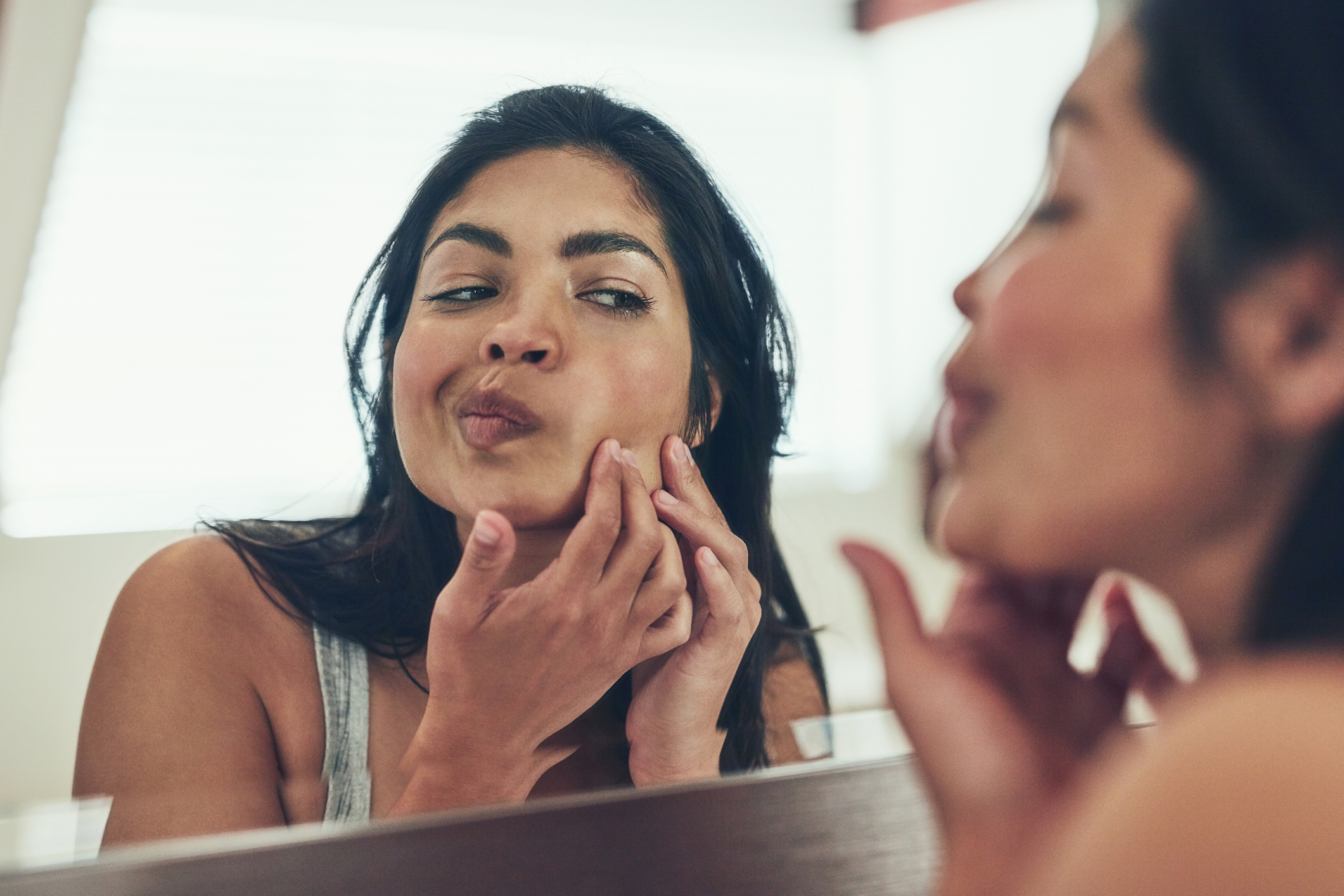 Mujer con espinillas frente al espejo