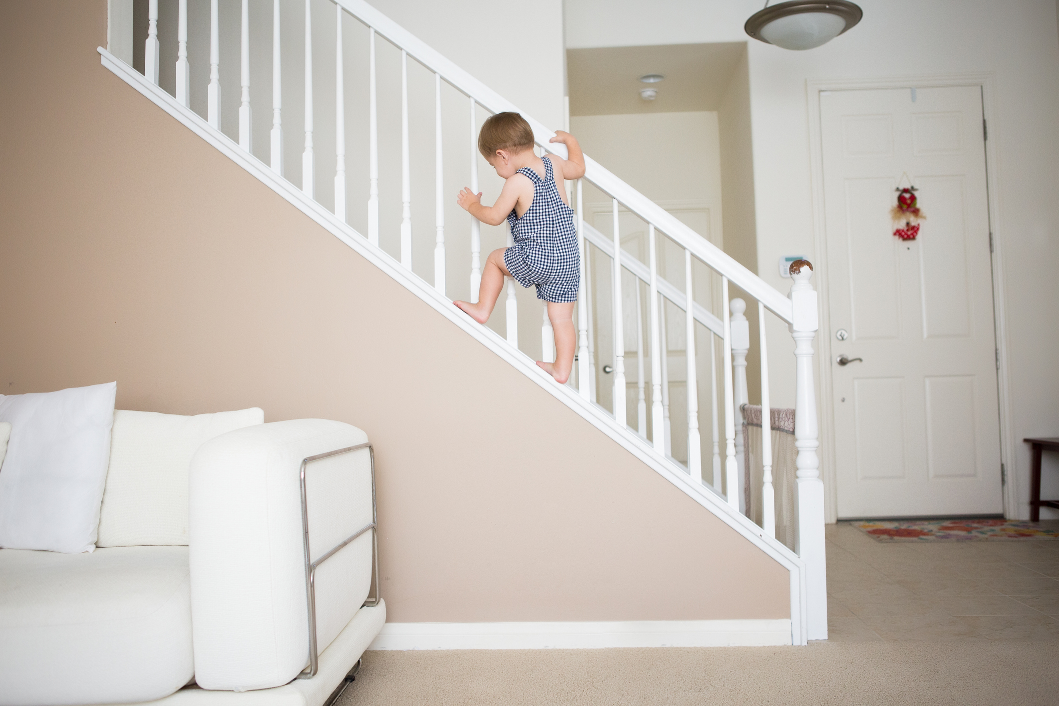 Cute toddler boy is climbing the stairways at home.