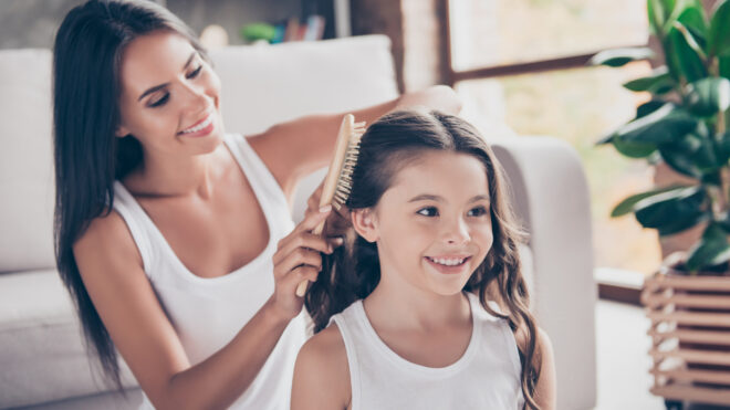 Mamá peinando a su hija con el cabello largo