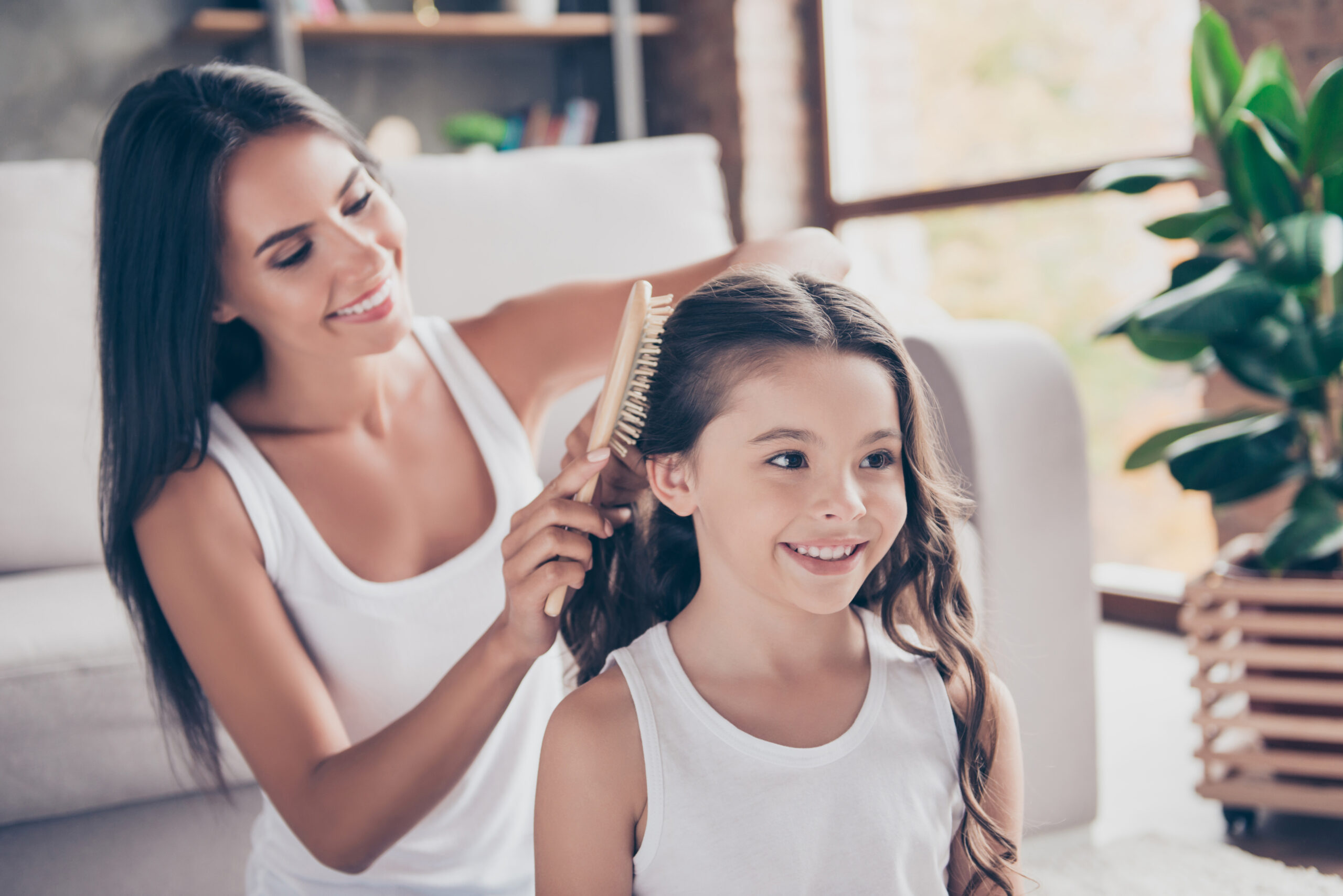 Mamá peinando a su hija con el cabello largo