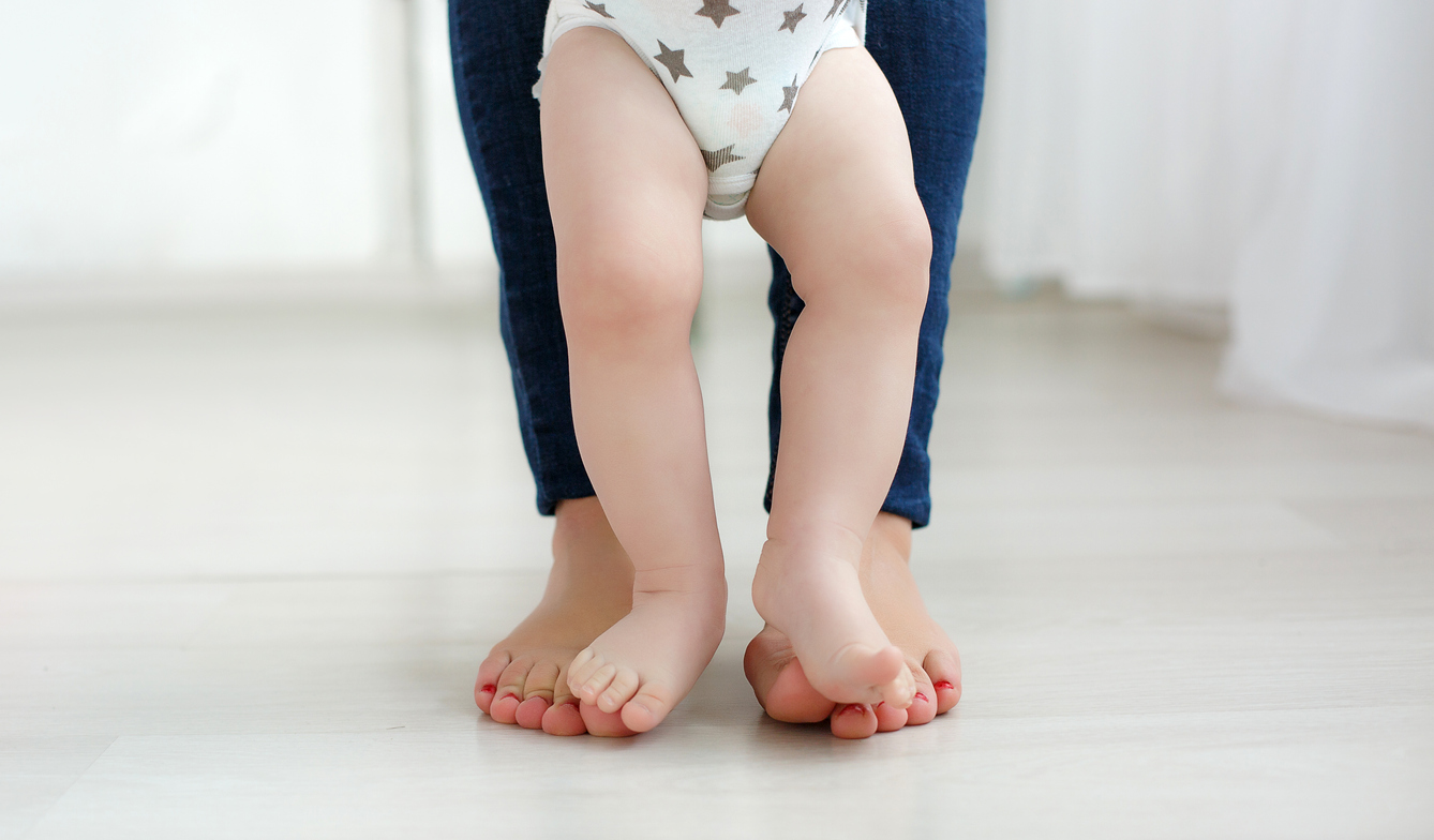 The bare feet of mother and baby on the floor in an empty room