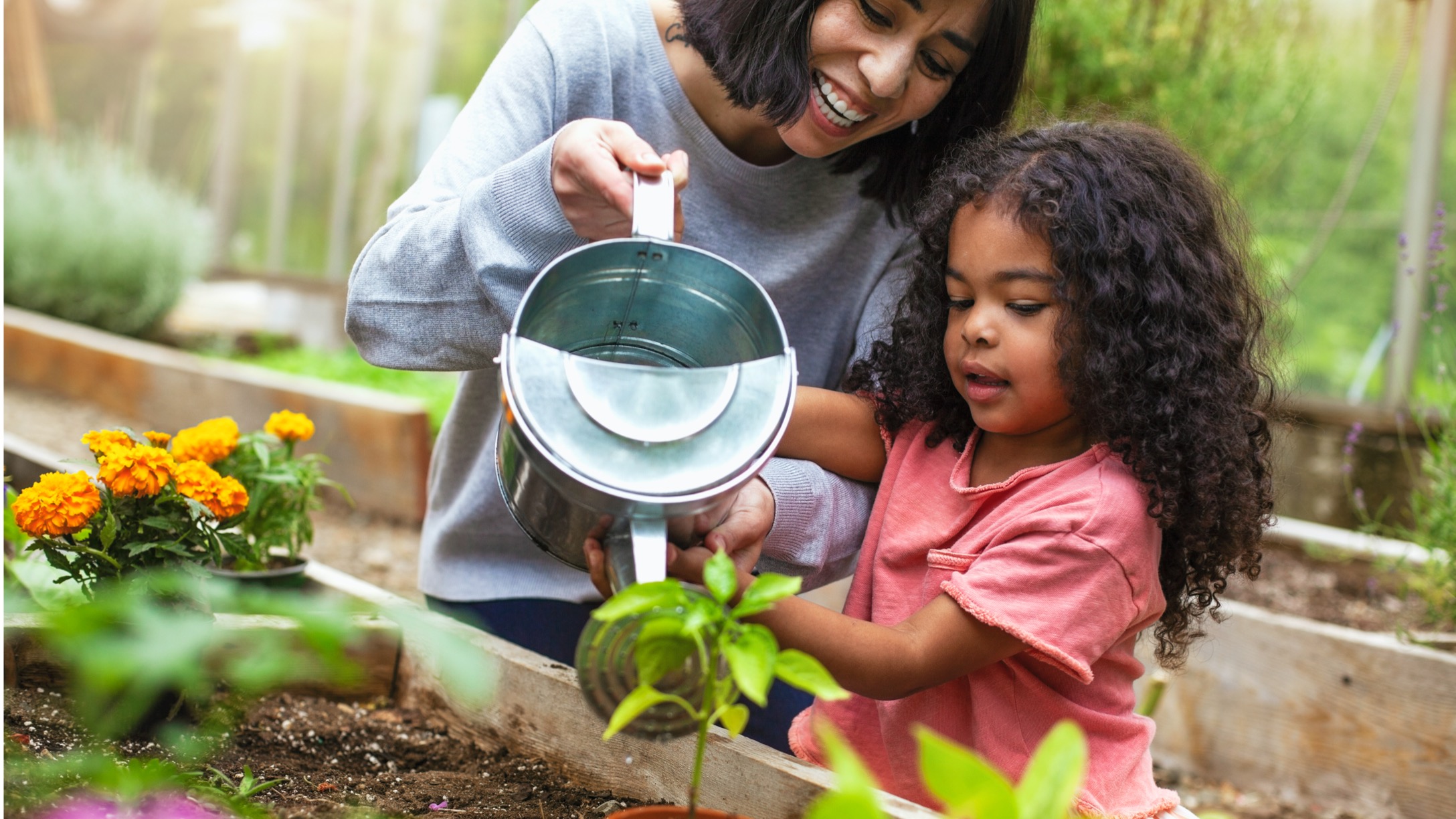 madre-e-hija-regando-planta-en-maceta-en-el-jard-C3-ADn-comunitario.jpg