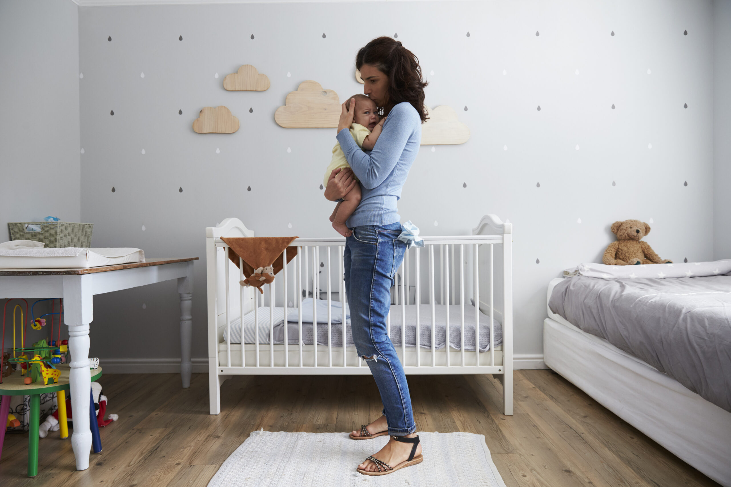 Mother Comforting Newborn Baby Son In Nursery