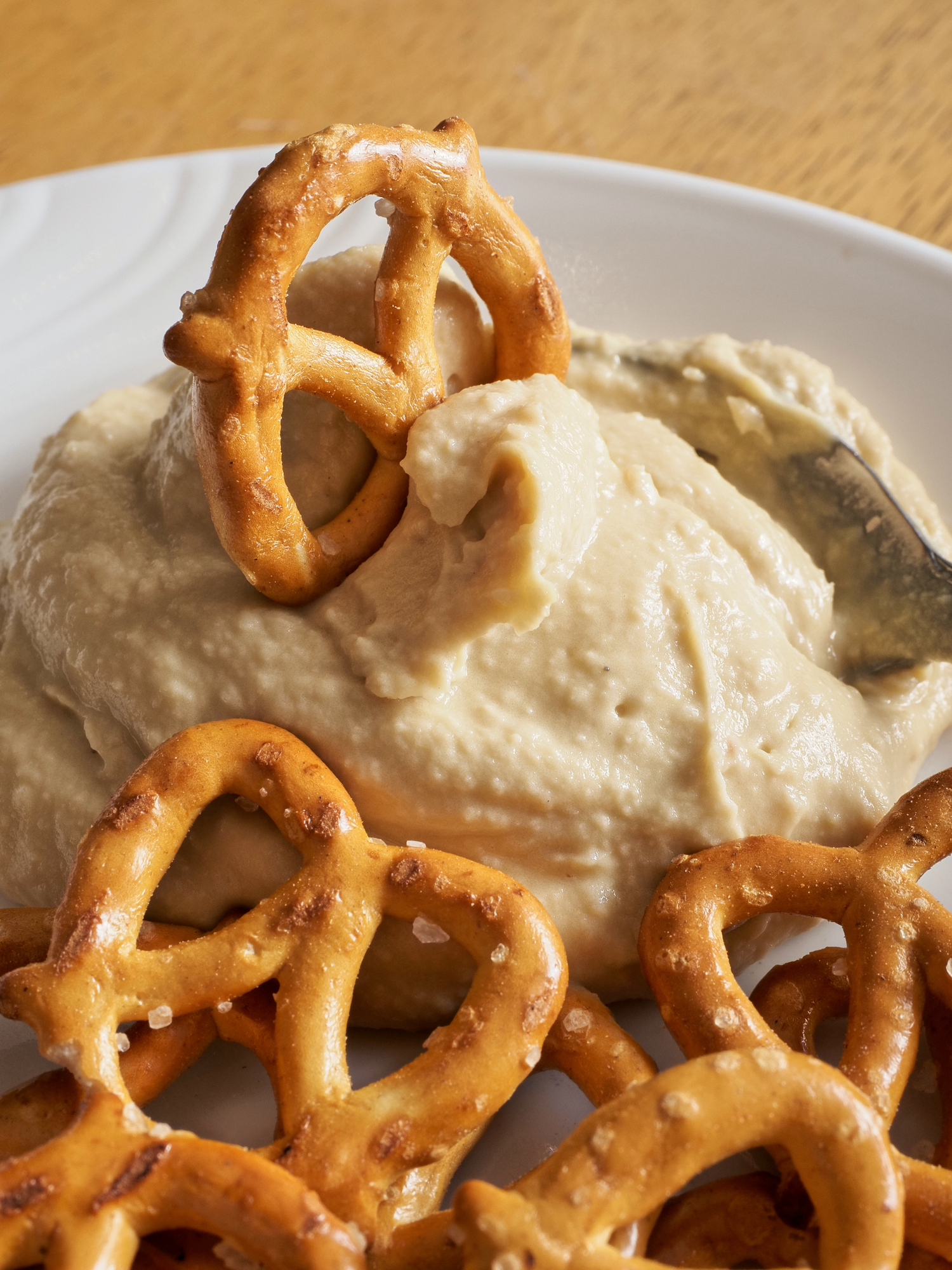 Smooth classic hummus on white plate with heart shaped pretzel twists