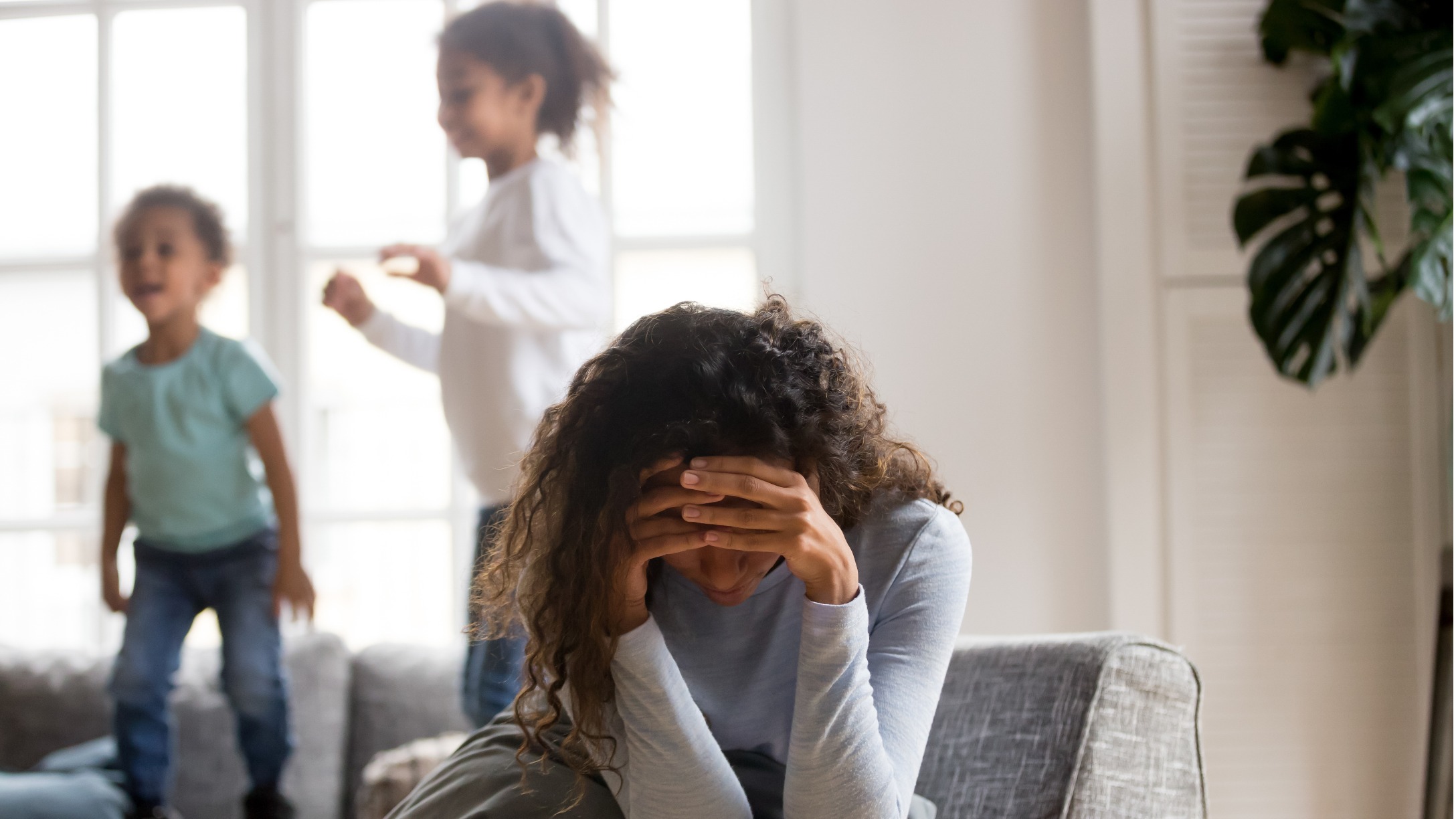 Mamá triste e hijas jugando tras ella