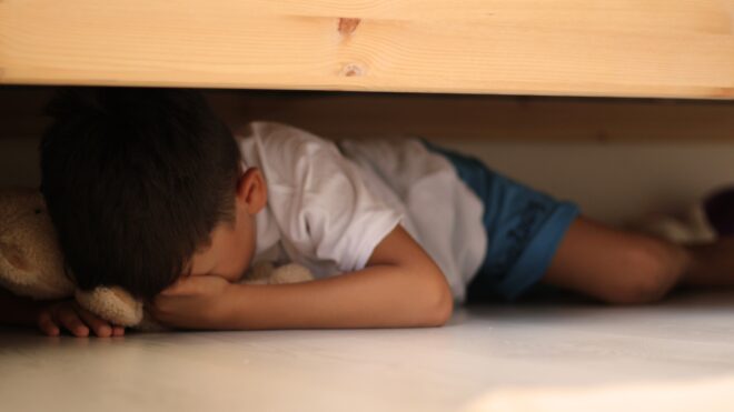 Niño asustado debajo de la cama