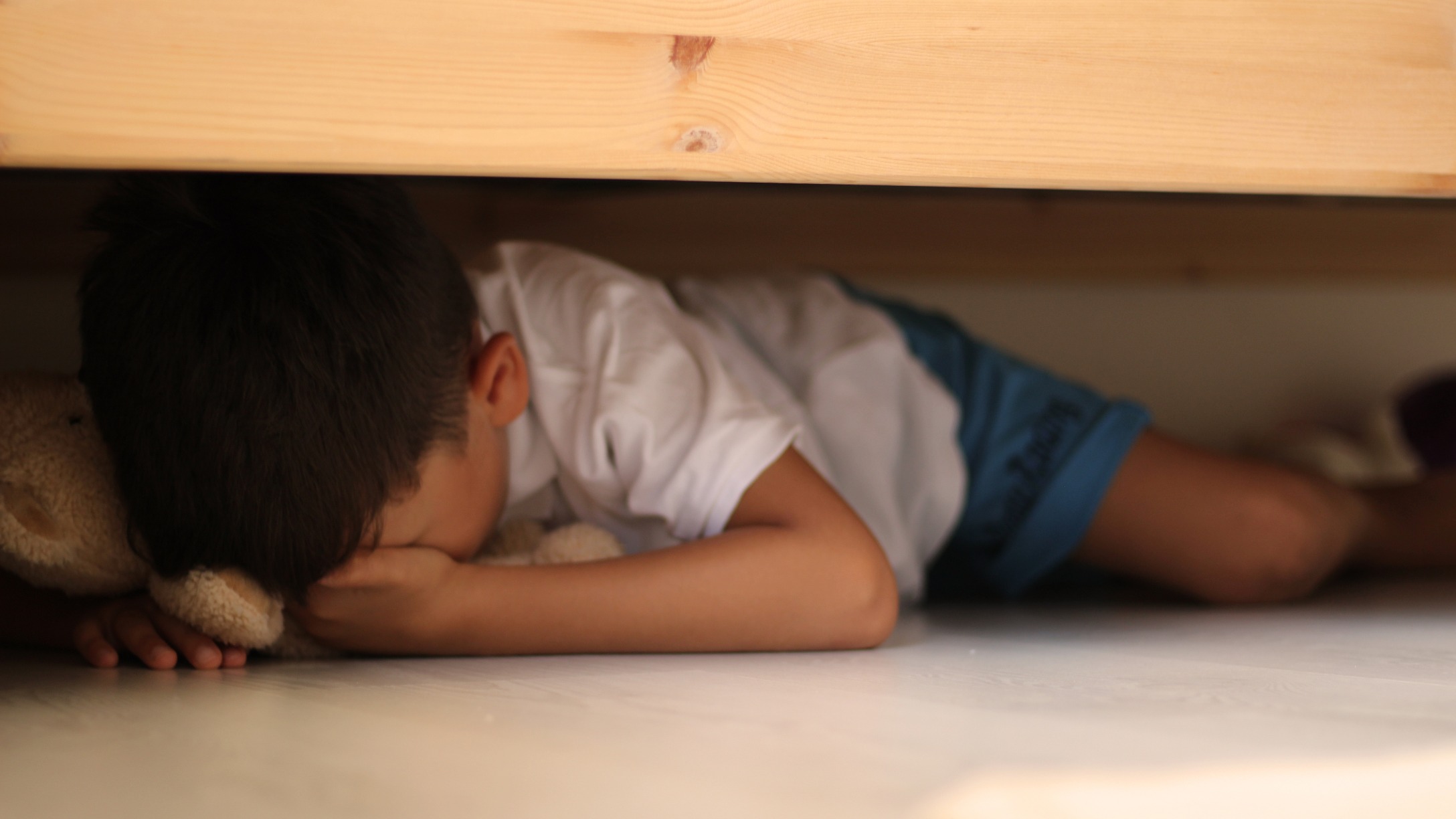 Niño asustado debajo de la cama