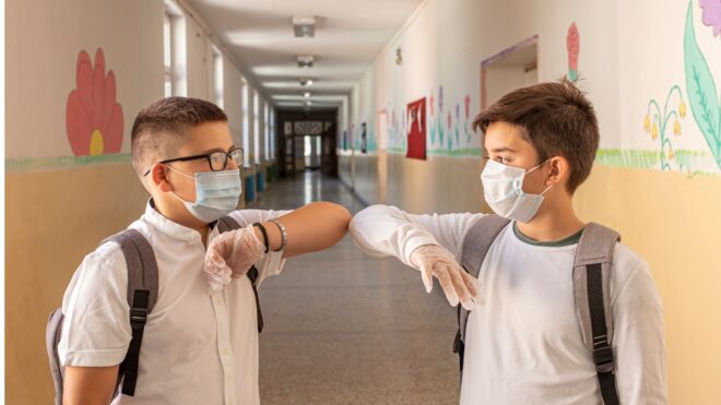 niños saludándose con el codo por distancia social en el regreso a clases