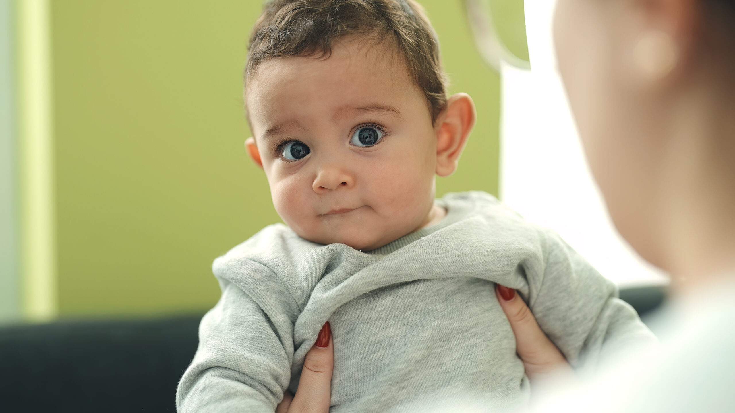 Adorable hispanic baby smiling confident relaxed on mother hands at home