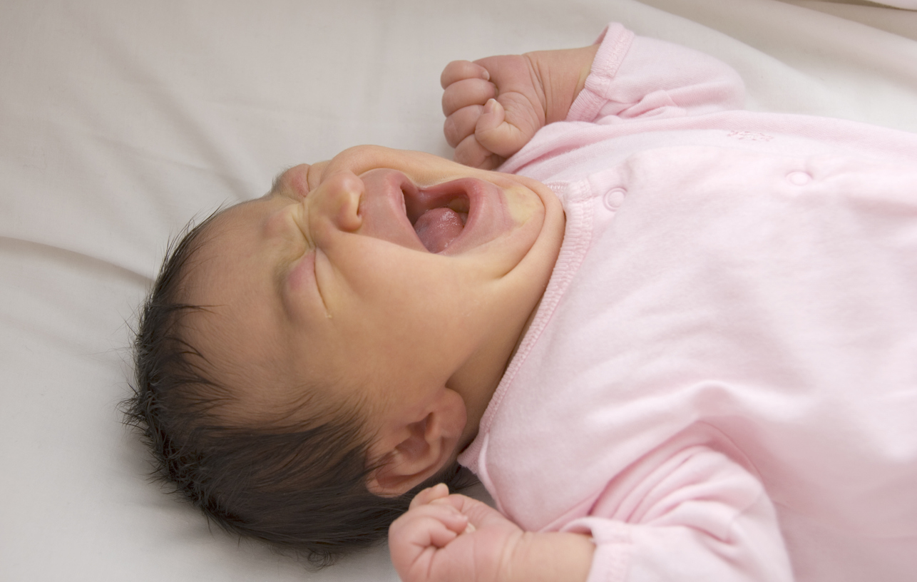 Crying newborn baby girl in pink clothes