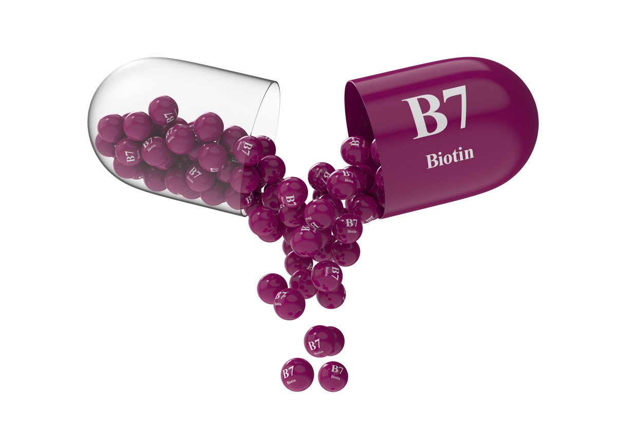 Open capsule with biotin from which the vitamin composition is pouring