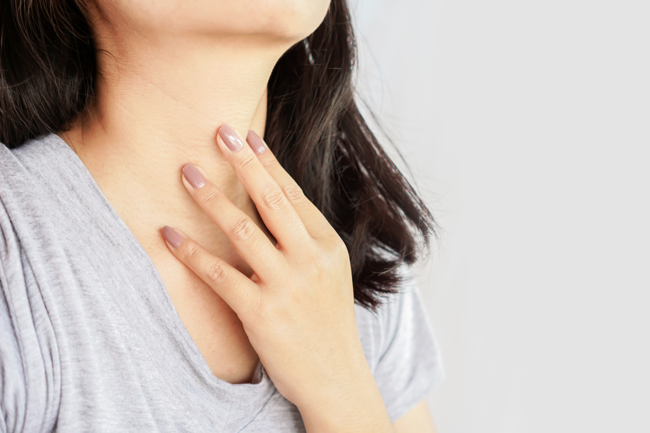 woman hand self checking thyroid gland on her neck