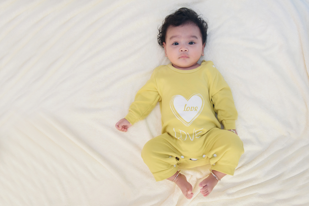 Top view portrait of cute Asian baby lying on the white bed sheet