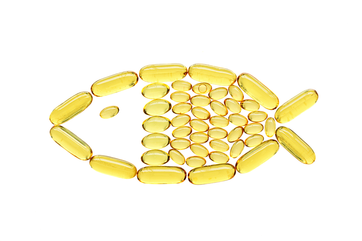 Transparent yellow medical capsules in fish shape, isolated on white background. Top view, health and care concept