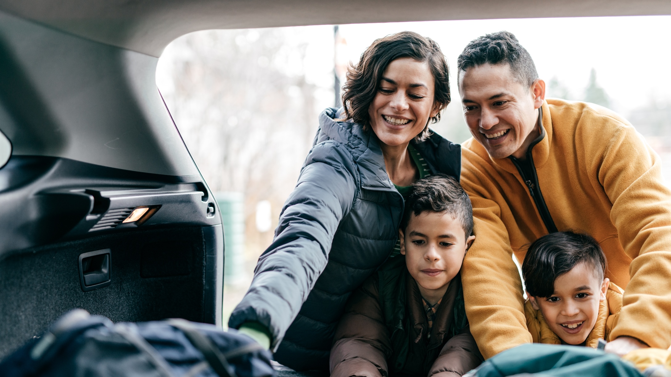 Latino family packing trunk for a road trip