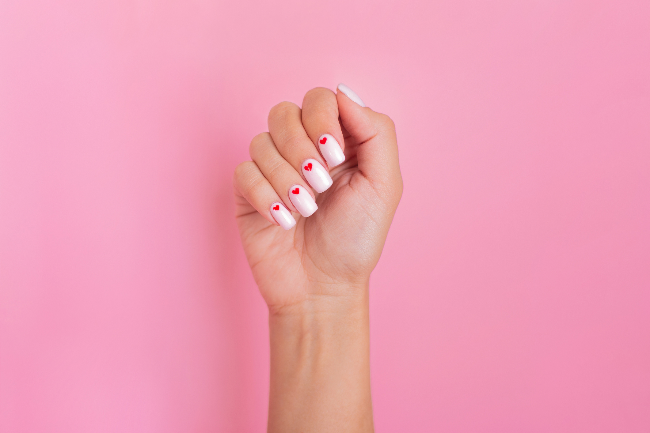 Beautiful female hand with white manicure, hearts design