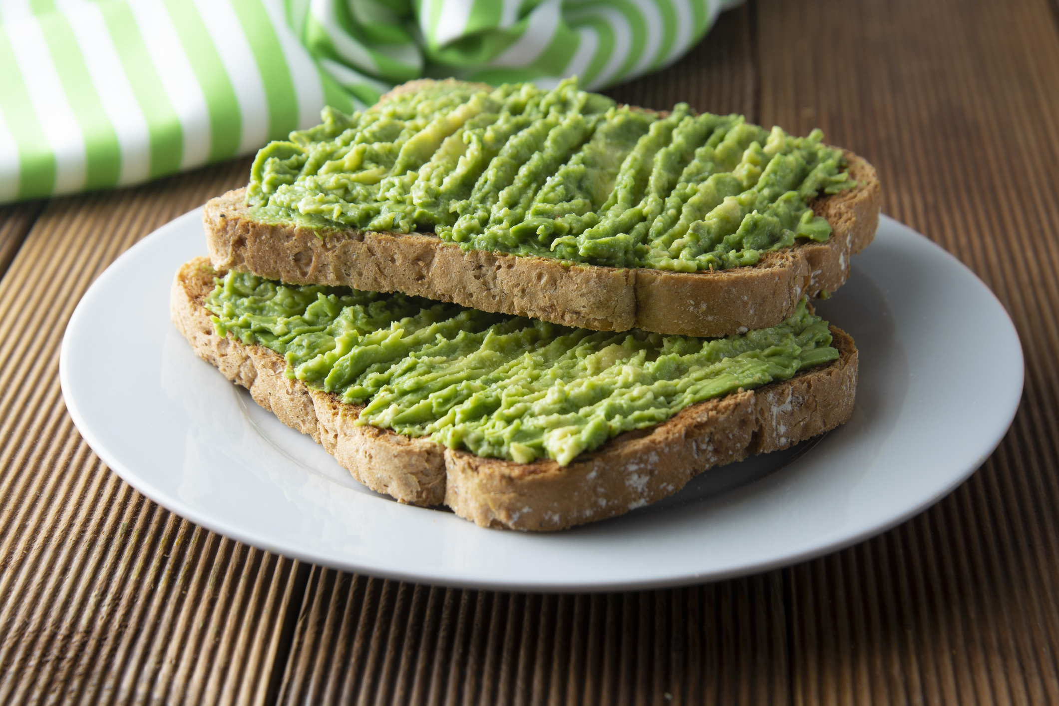 Healthy avocado sandwich, toast bread. Mushed avocado paste, on wooden background. Guacamole.