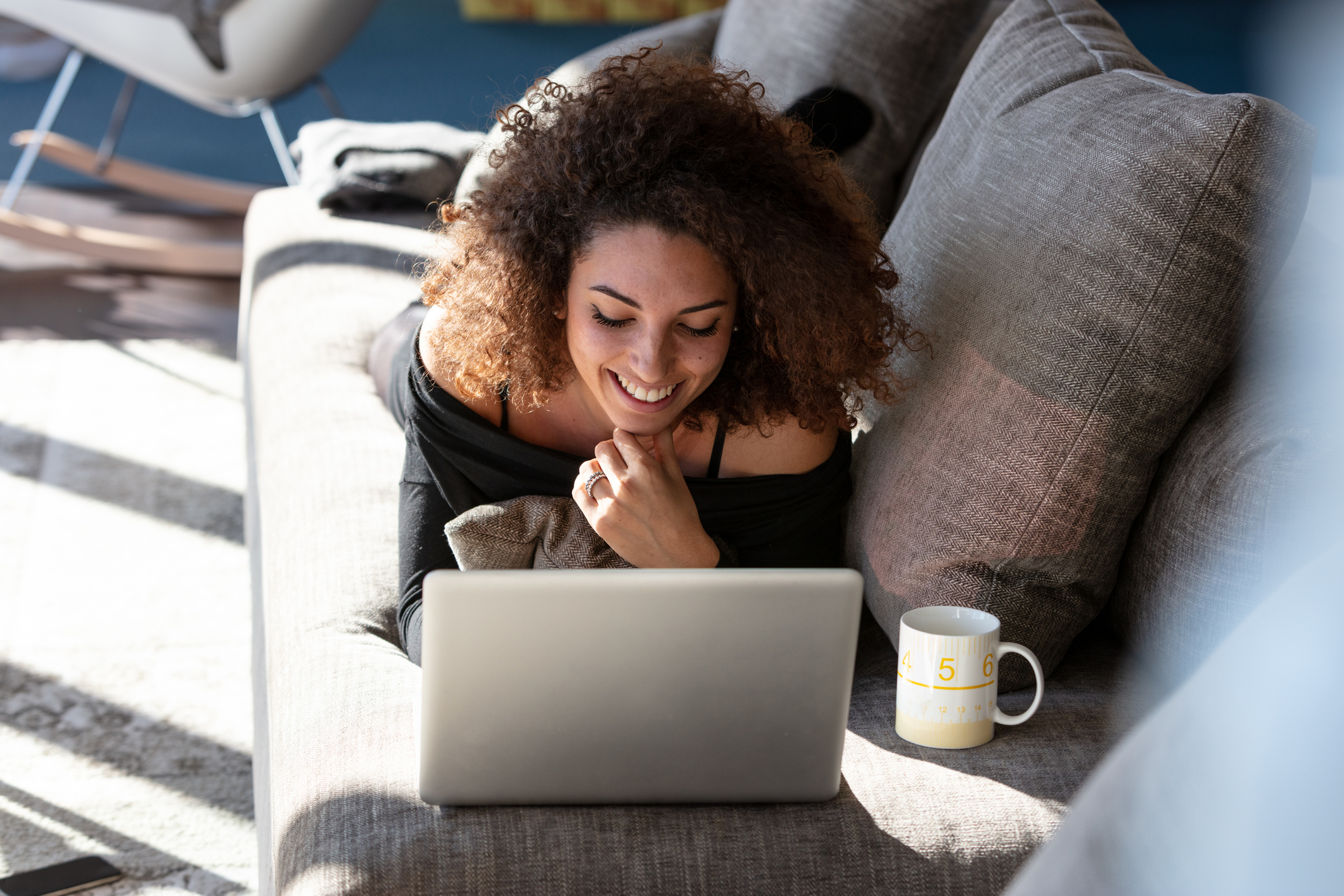 Young woman lies on a couch with laptop computer