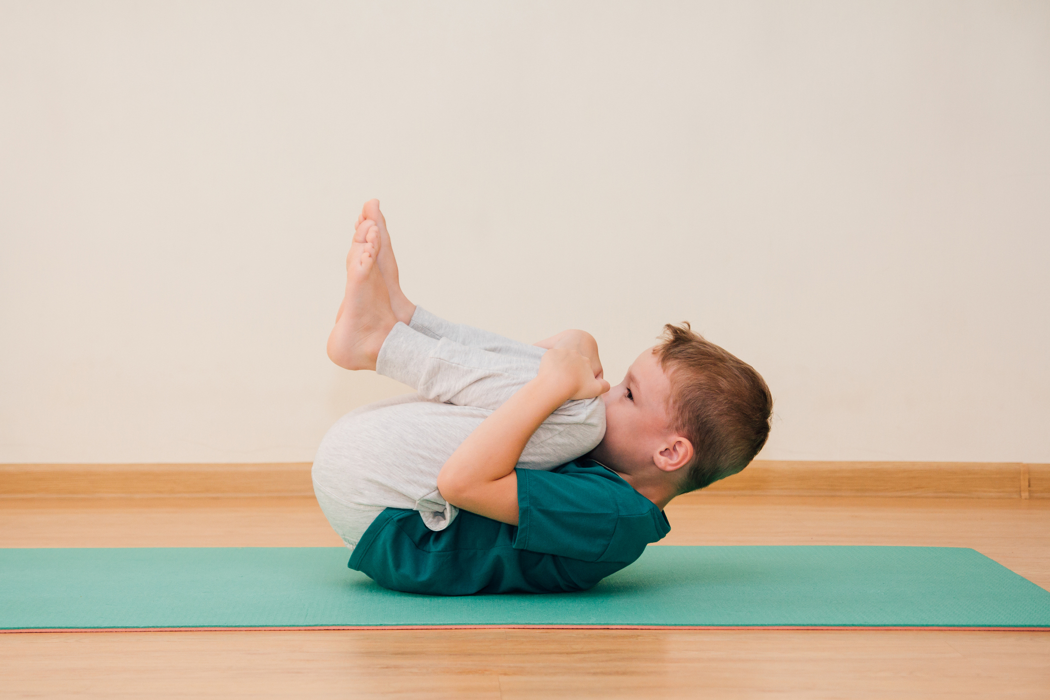 Cute little boy is learning to do yoga in the gym