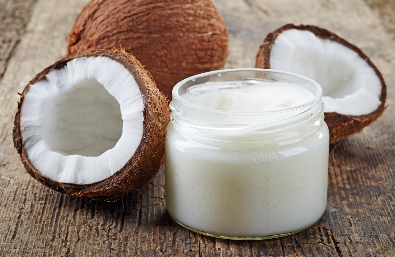 Fresh coconuts and a jar of coconut oil on a wooden table