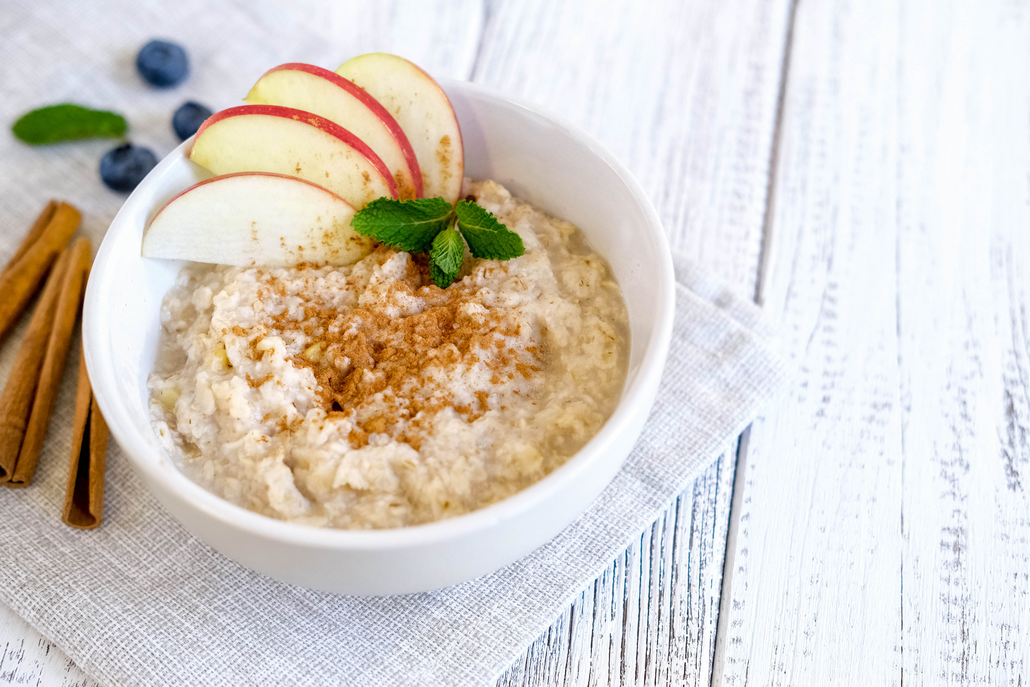 Delicious porridge with apple and cinnamon. Fresh natural breakfast served on wooden table