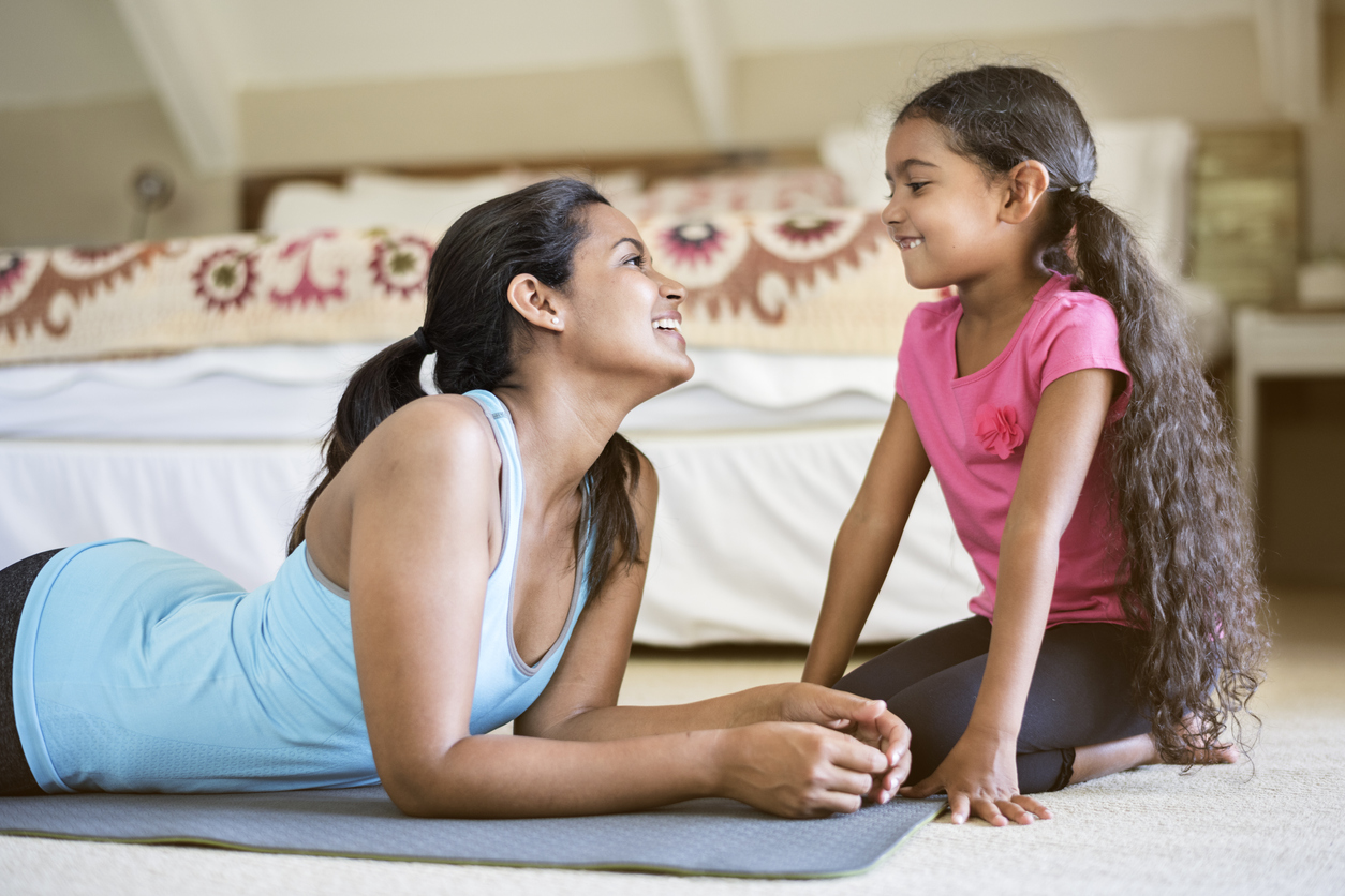 Woman looking at daughter while exercising at home