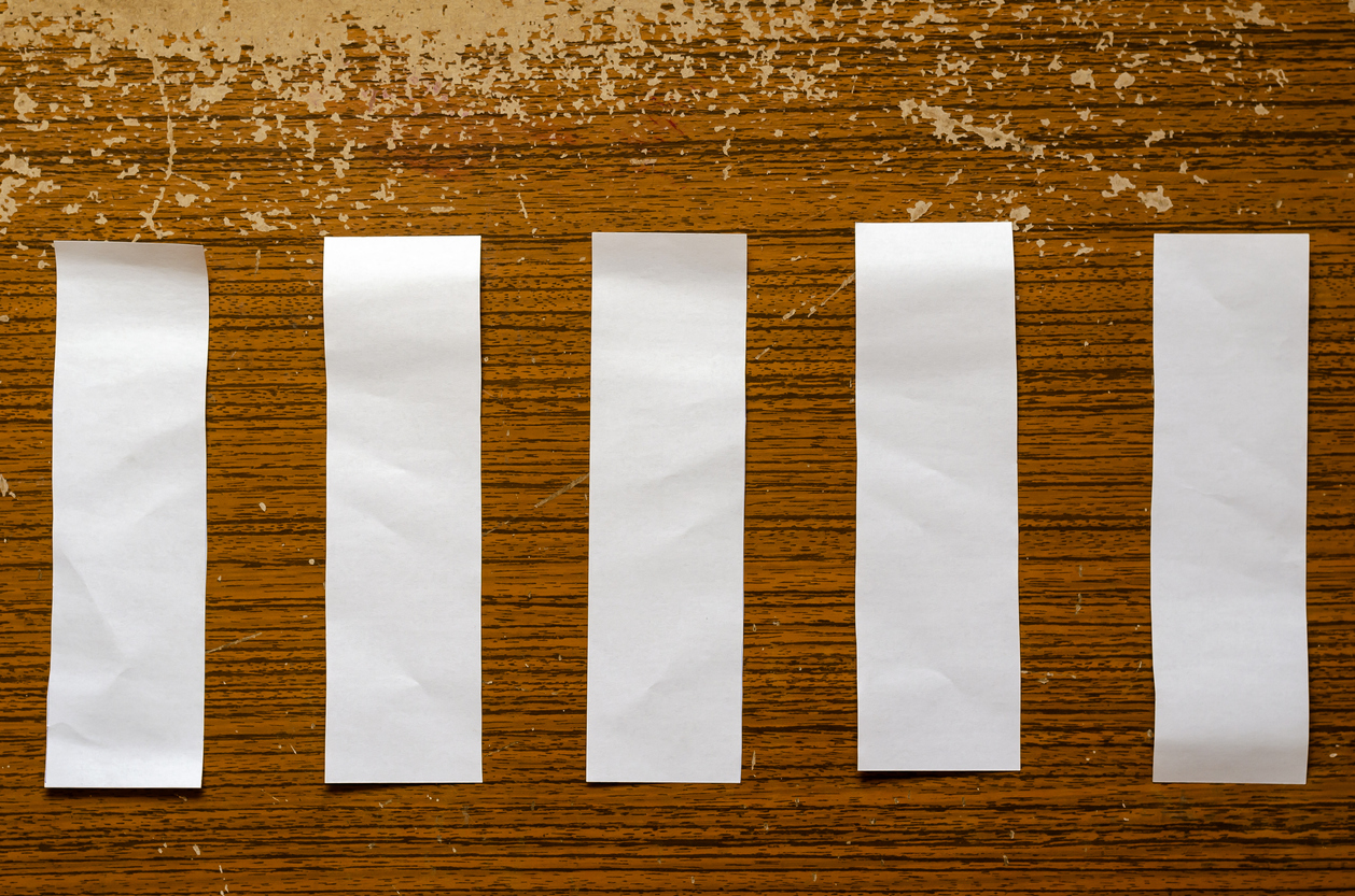 Five empty paper sheets on a brown wooden background.