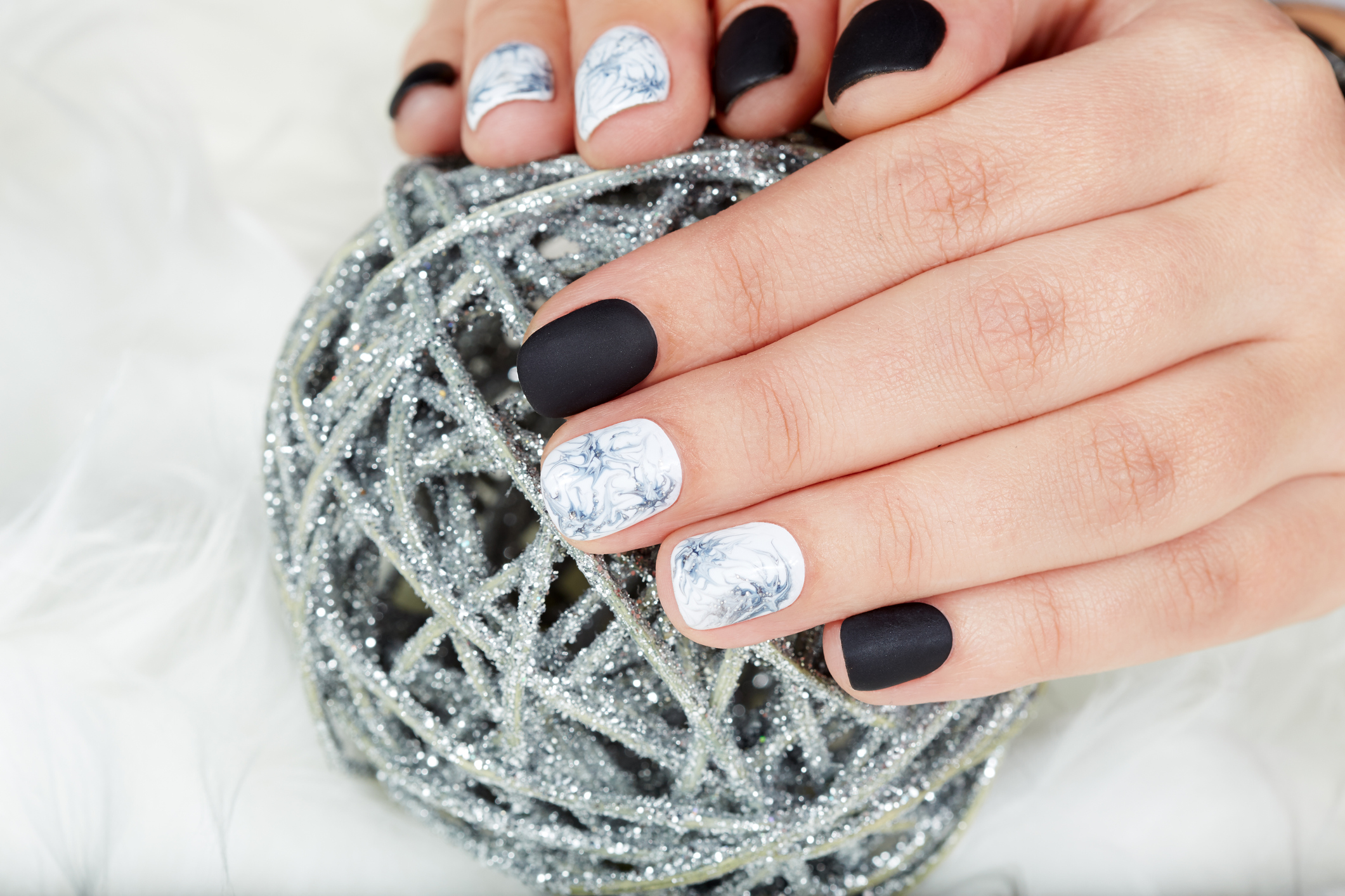 Hands with manicured nails colored with black and white nail polish