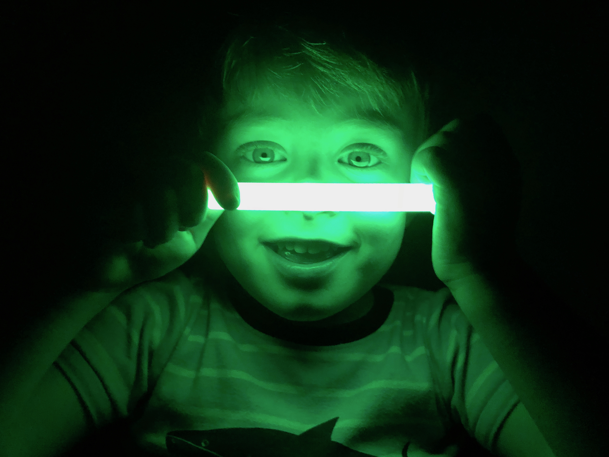 Smiling boy with glow stick, dark background