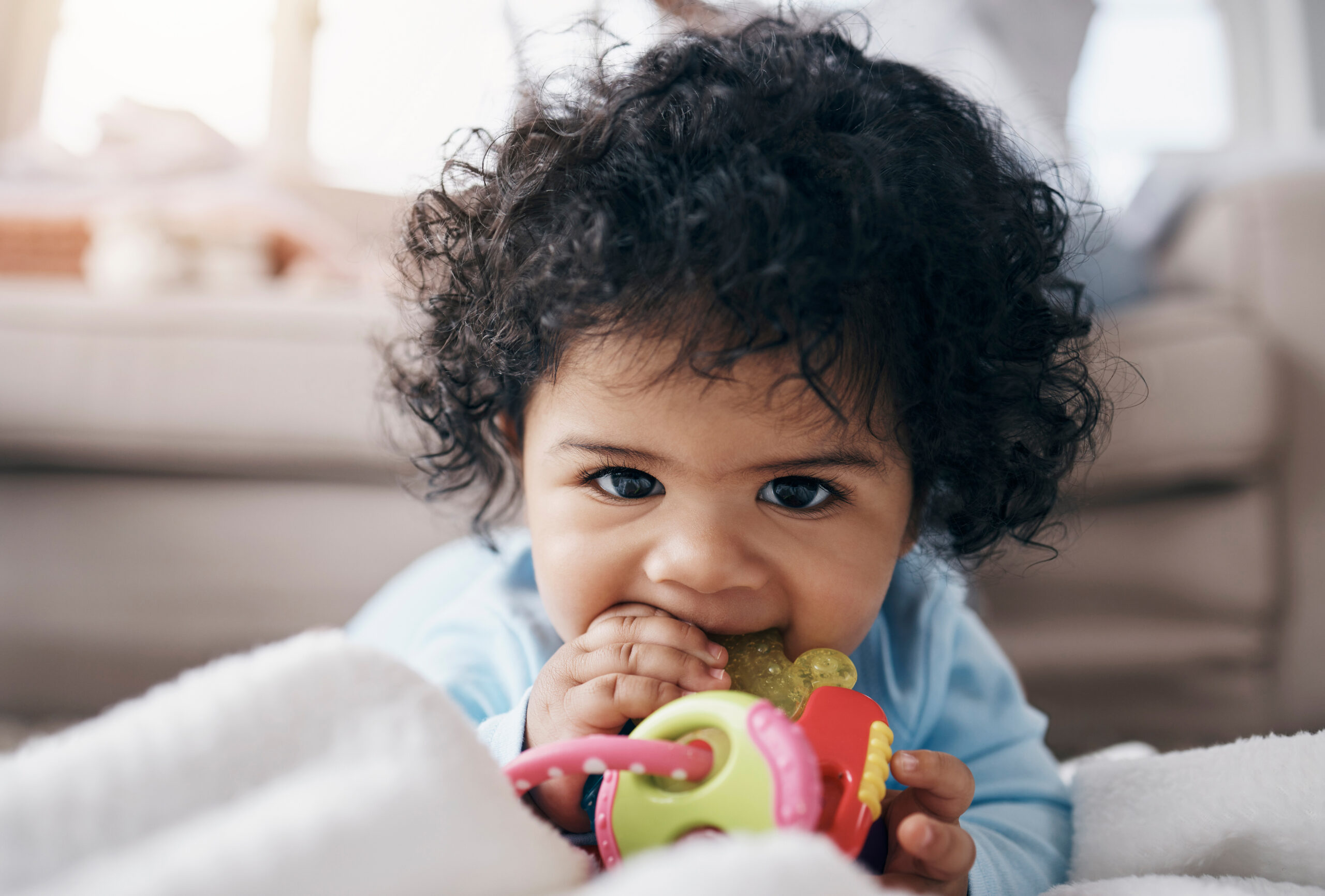 Shot of an adorable little girl lying on the floor in the living room and playing with a toy