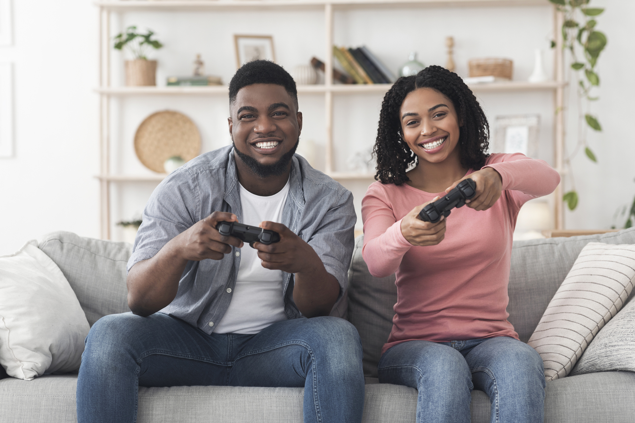 Cheerful black guy and girl playing video games at home