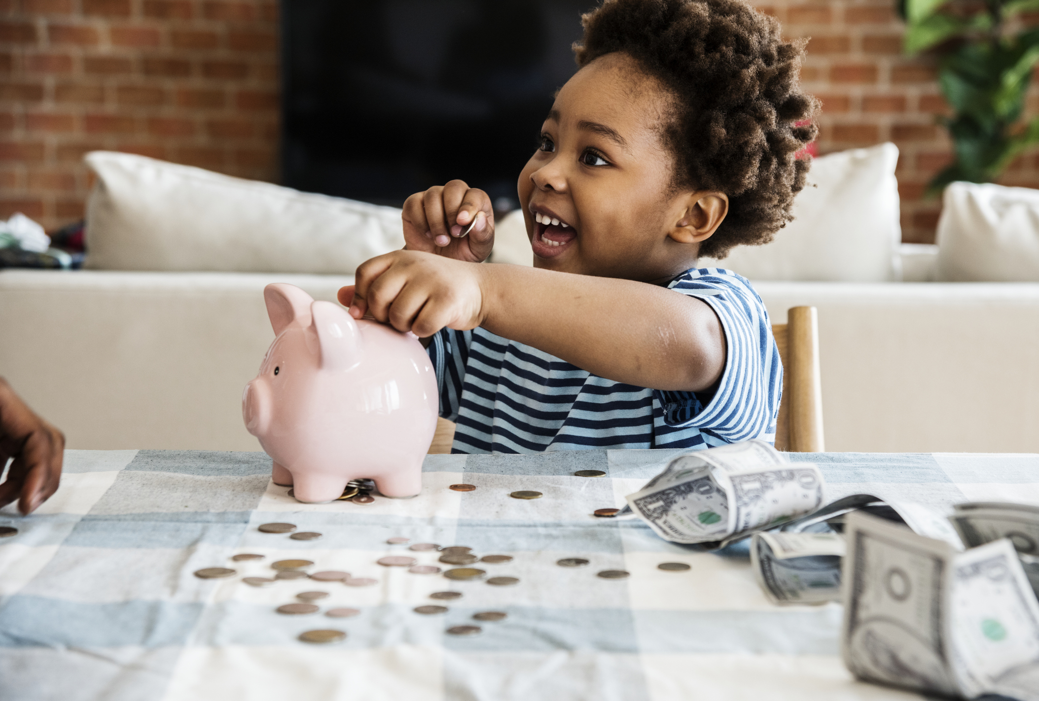 Black boy collecting money to piggy bank