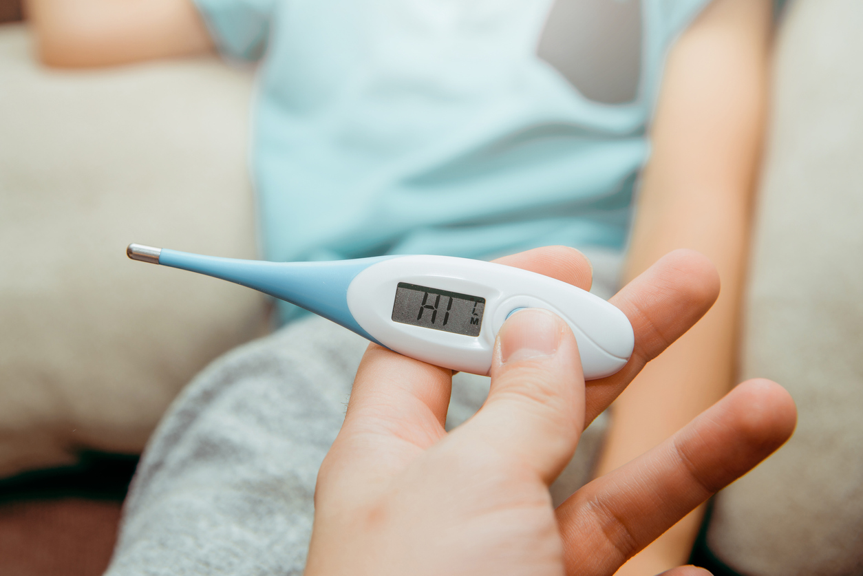 The child measures the fever with an electronic thermometer.