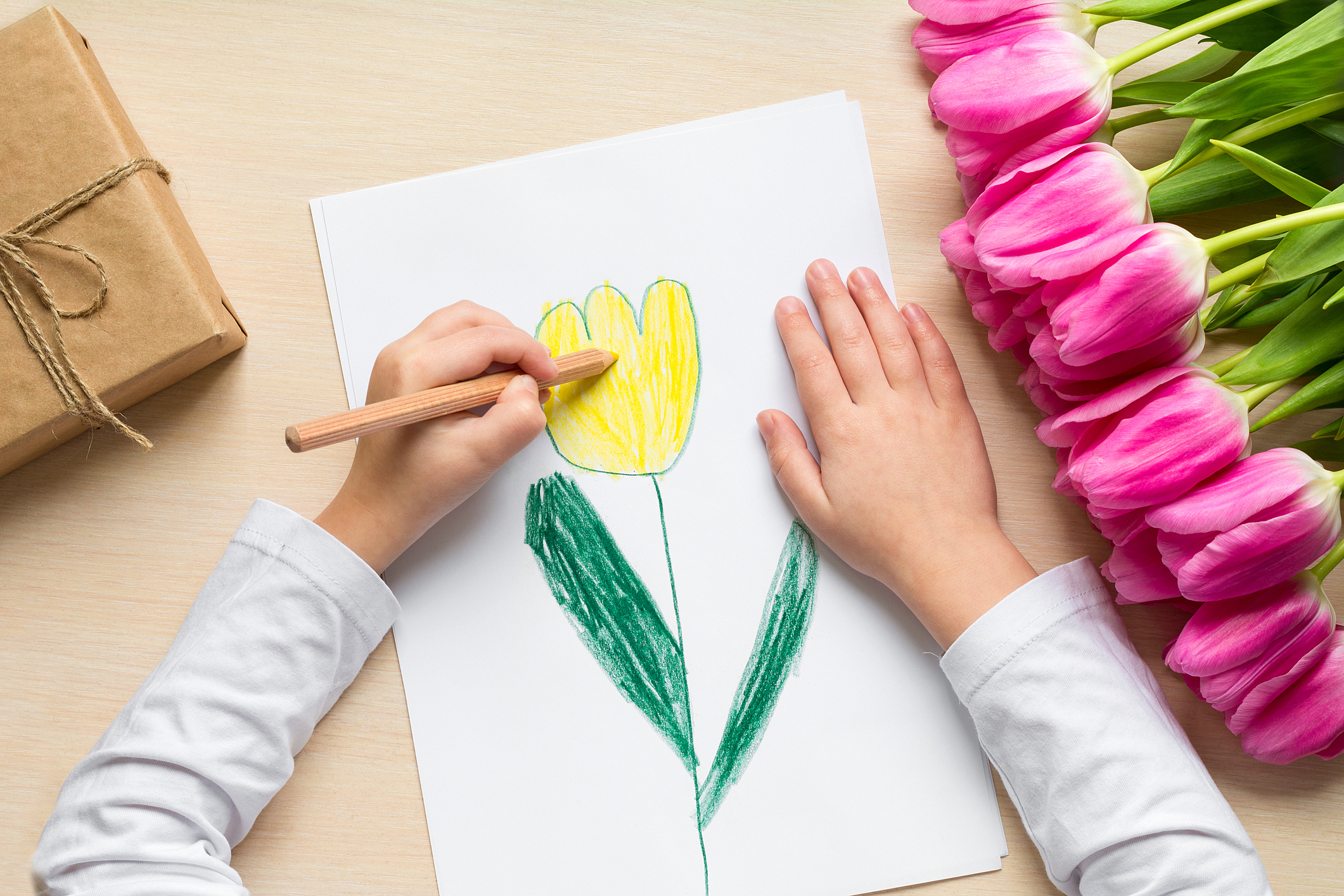 Little boy paints greeting card for Mom on Mother's Day or 8 March. Top view