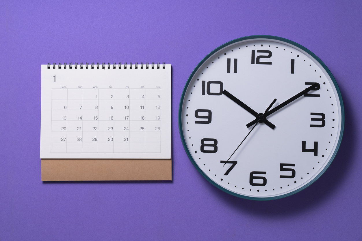 close up of calendar page and clock on the purple table background, planning for business meeting or travel planning concept