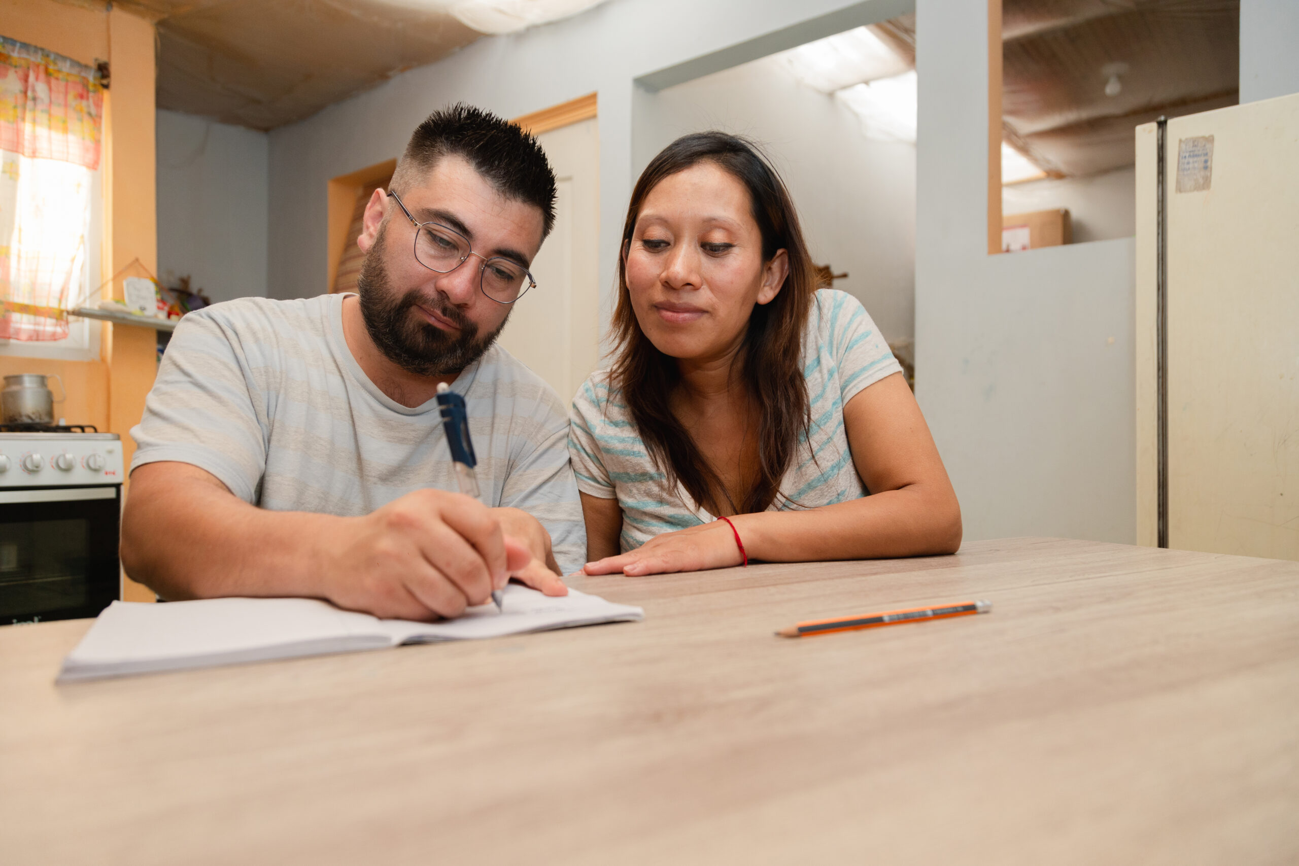 Happy married couple at home calculating household expenses. couple doing their accounts in the living room at home - Hispanic couple at home